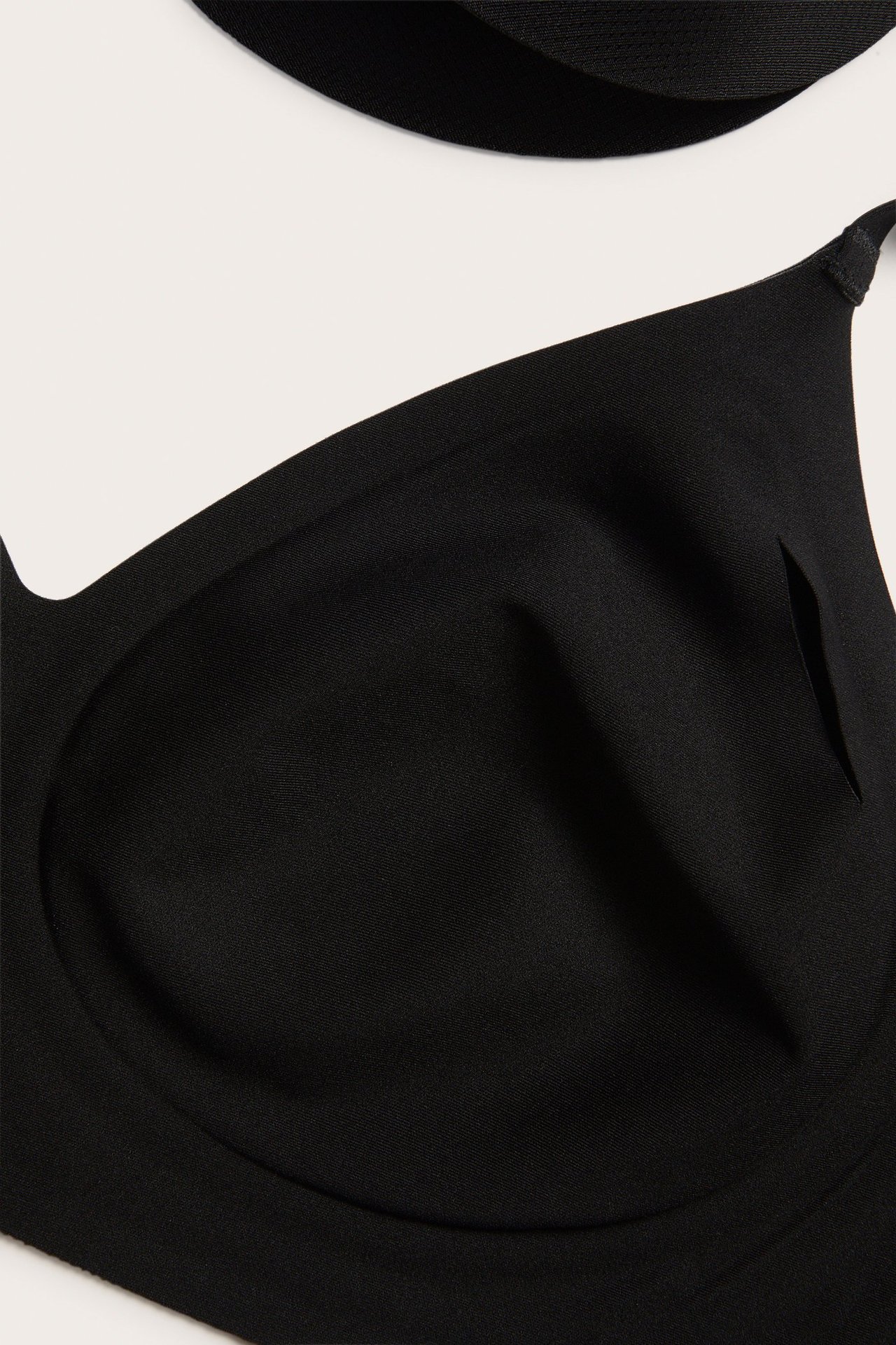 Zbliżenie czarnego biustonosza bez fiszbin z mikrofibry, z bezszwowymi krawędziami i wyjmowanymi wkładkami.