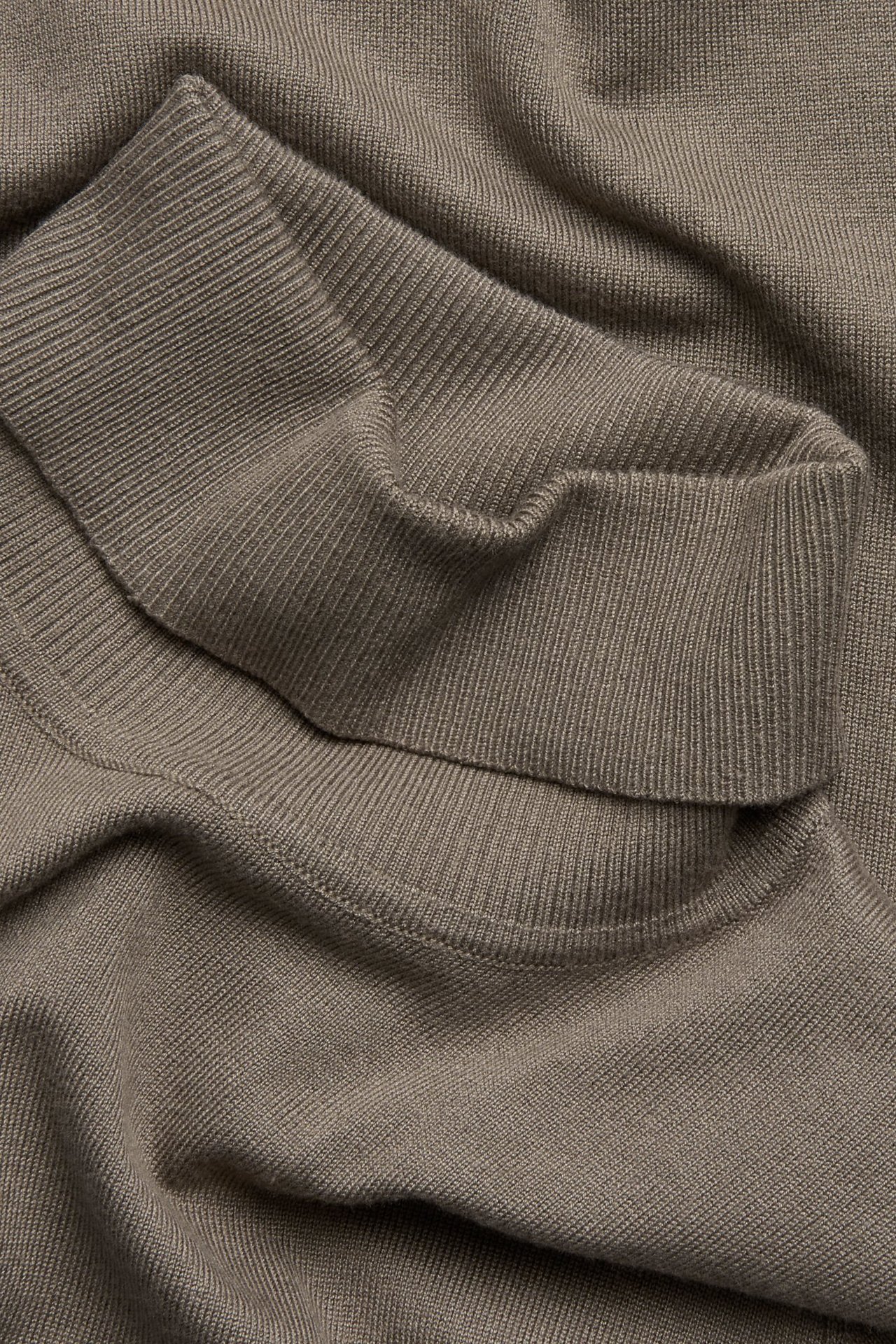 Zbliżenie jasnobrązowego, drobno dzianego golfu z mieszanki wiskozy.