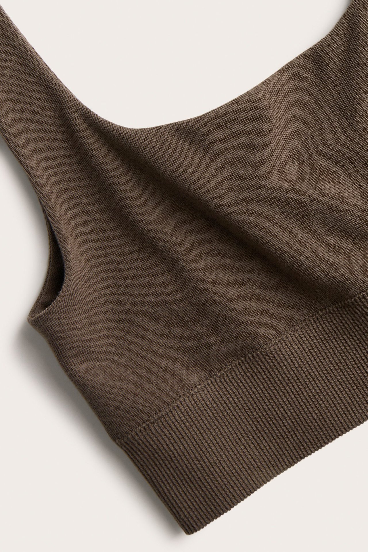 Zbliżenie na ciemnobrązowy top biustonoszowy z mieszanki bawełny, z prążkowaną fakturą i szerokim ściągaczem.