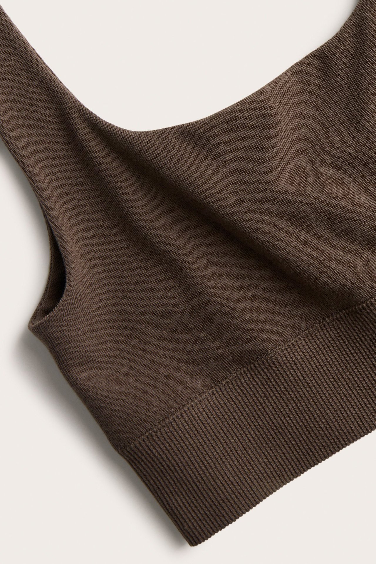 Närbild av en mörkbrun bh-topp i bomullsmix med breda band och ribbad nederkant.