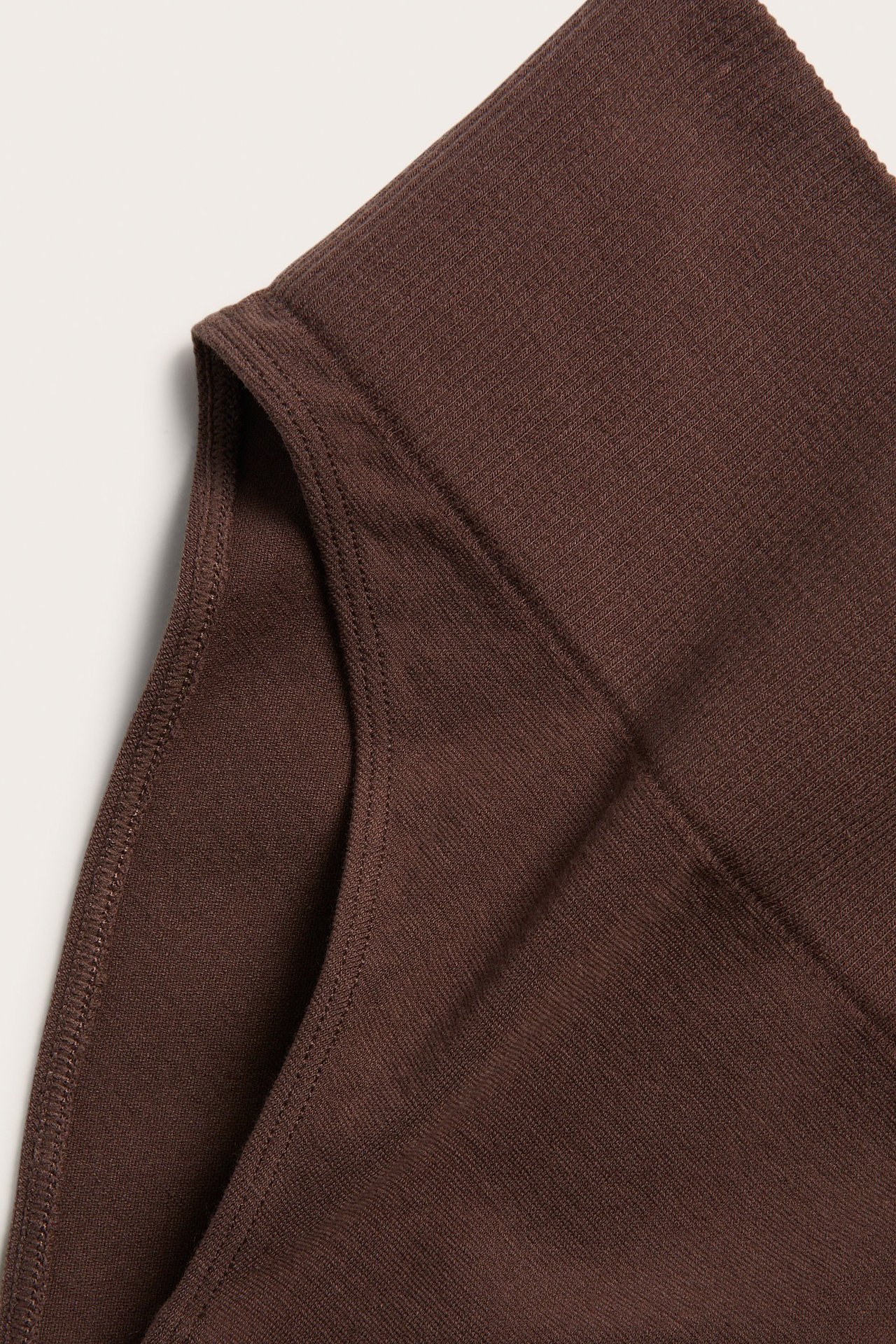 Zbliżenie na ciemnobrązowe, bezszwowe figi Brazilian z prążkowanym pasem z miękkiej bawełny.