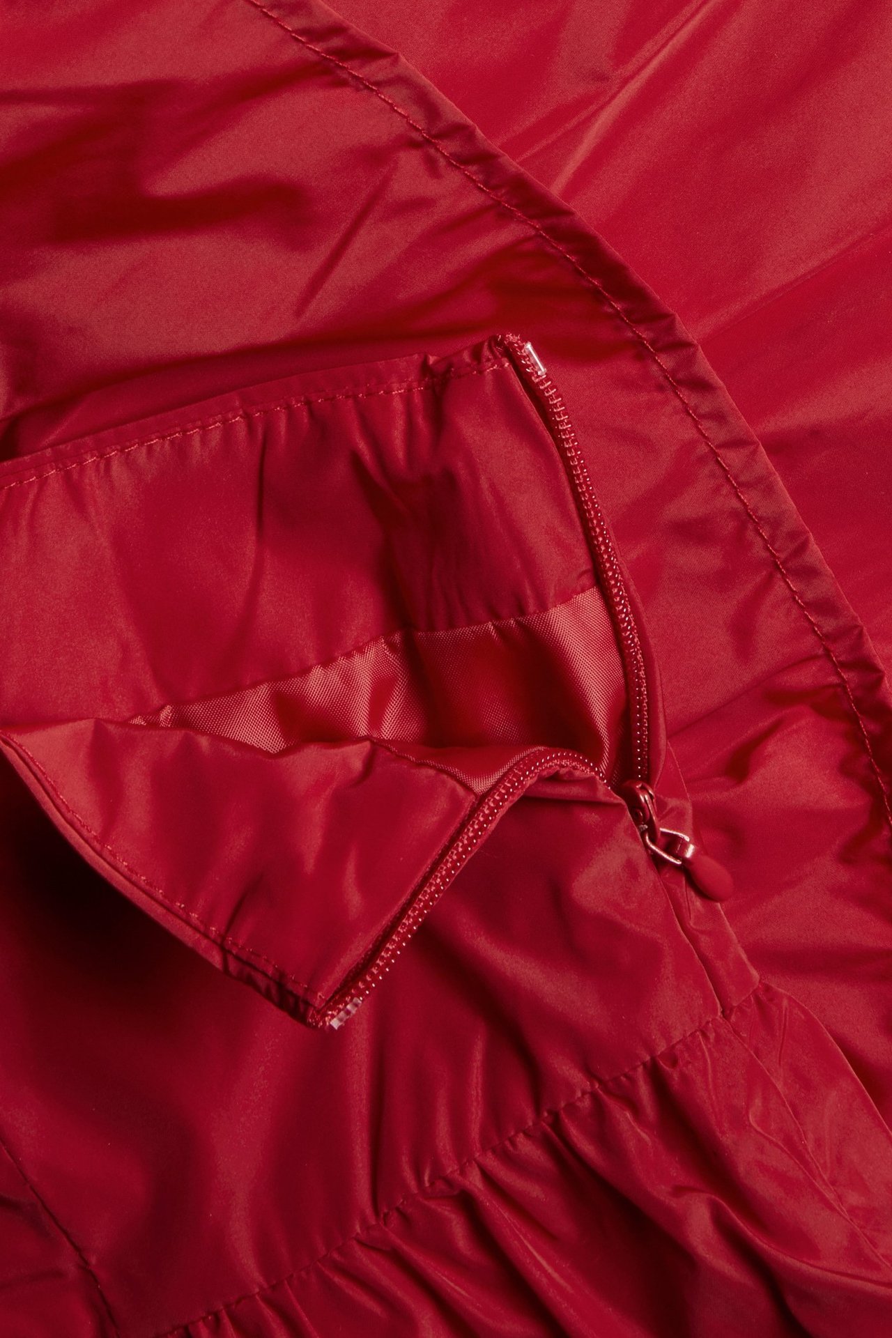 Zbliżenie na czerwoną krótką spódnicę z falbankami z częściowo rozpiętym bocznym zamkiem.