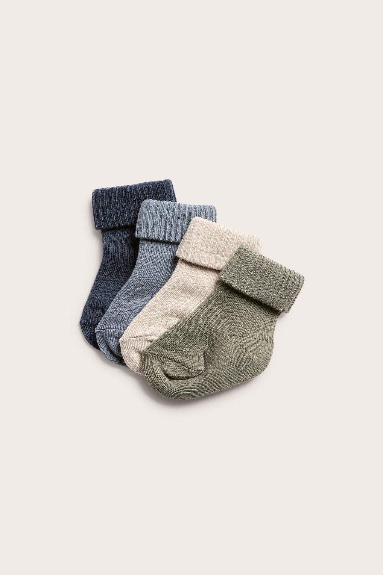 Ovenfra fire par ribbestrikkede babysokker i mørkeblått, lyseblått, beige og olivengrønt.