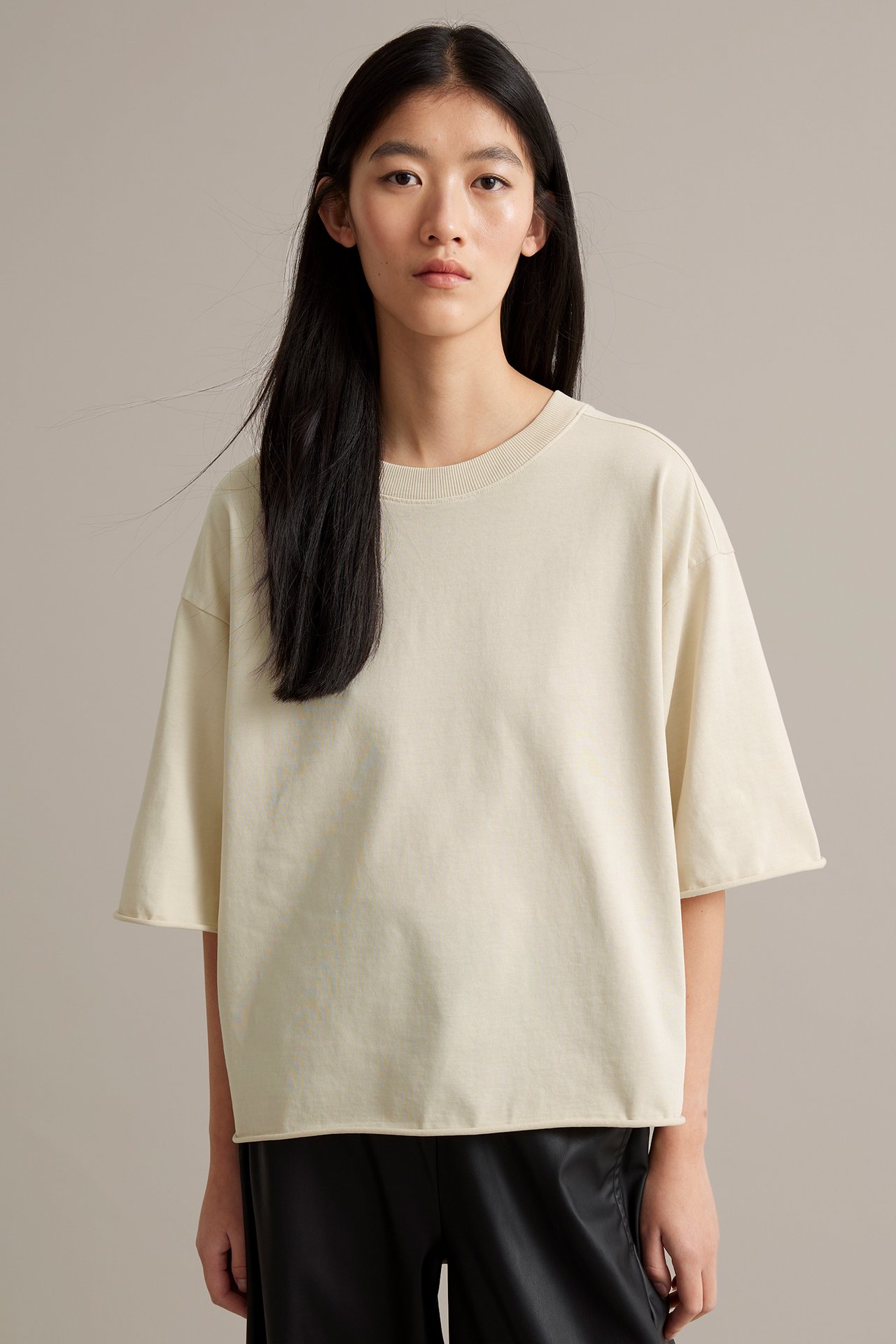 Ljusbeige T-shirt i kraftig trikå med tvättad look och råa fållar, dammodell.