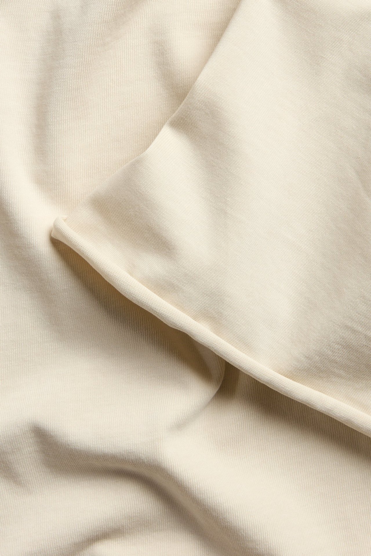 Ljusbeige T-shirt i kraftig trikå, tvättad look, råa fållar, dammodell, frontvy.