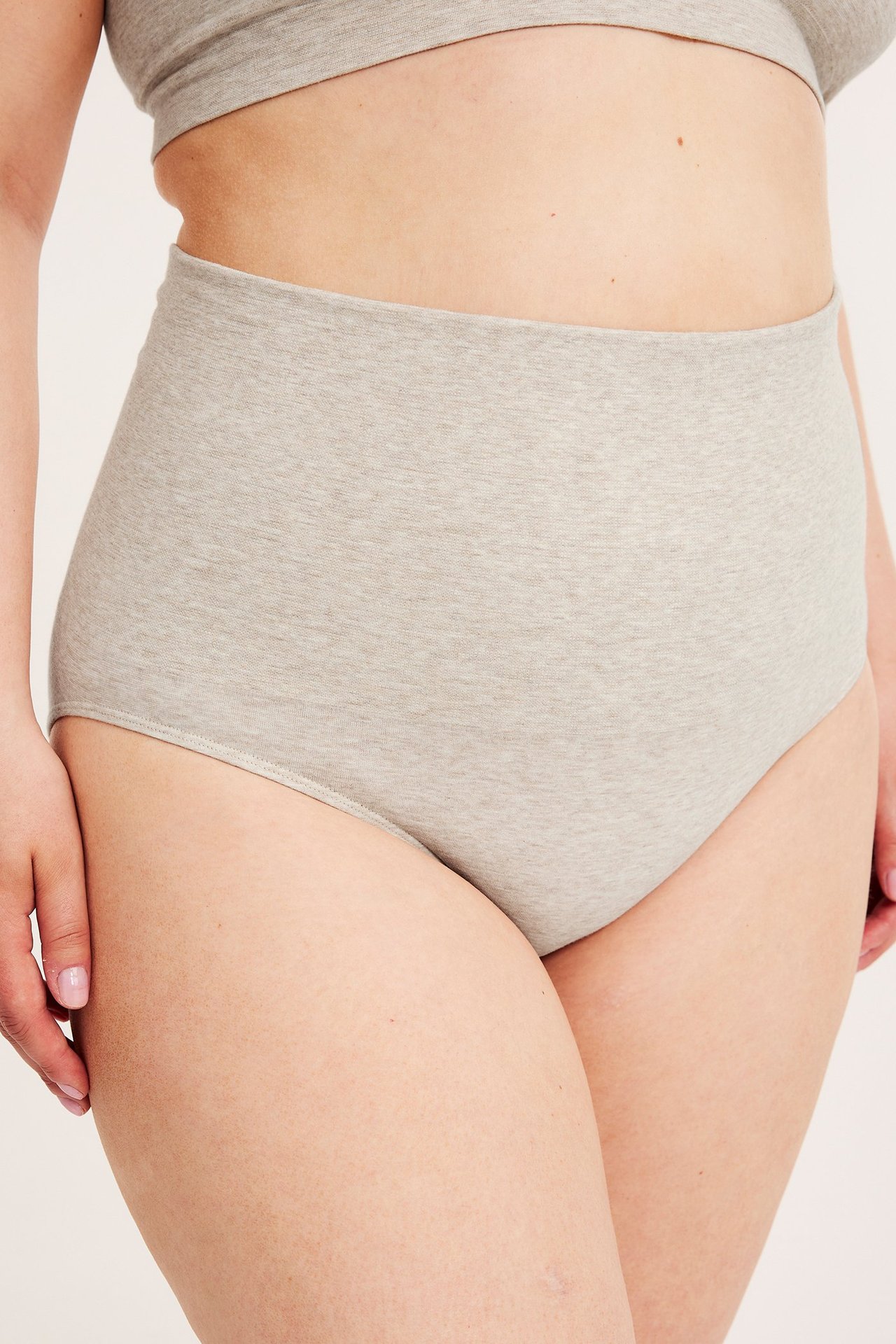 Lähikuva naisesta yllään melange-beiget saumattomat korkeavyötäröiset alushousut ja yhteensopiva rintaliivitoppi.