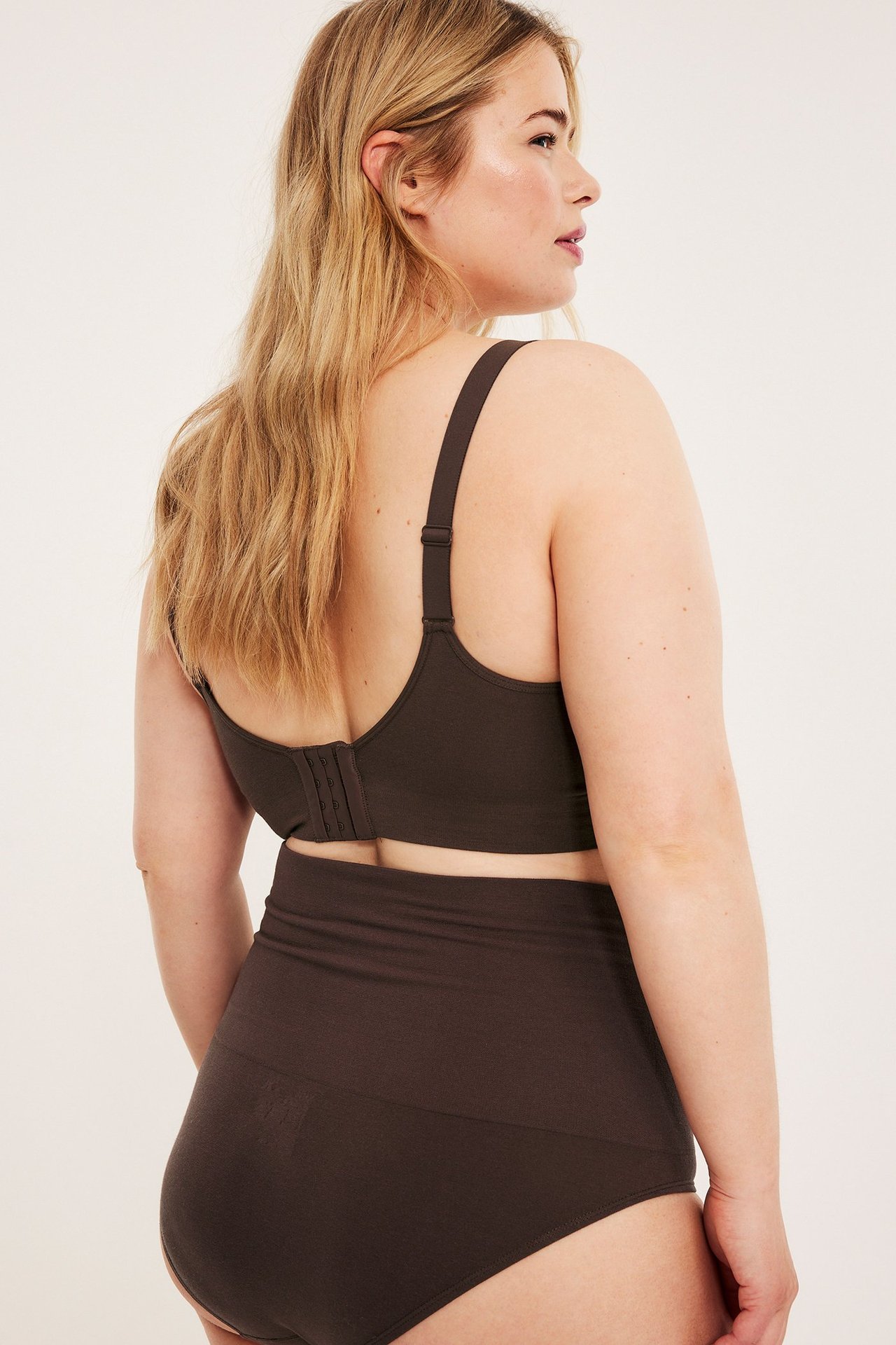 Bakifrån på kvinna i mörkbrun sömlös trosa med hög midja och matchande BH.
