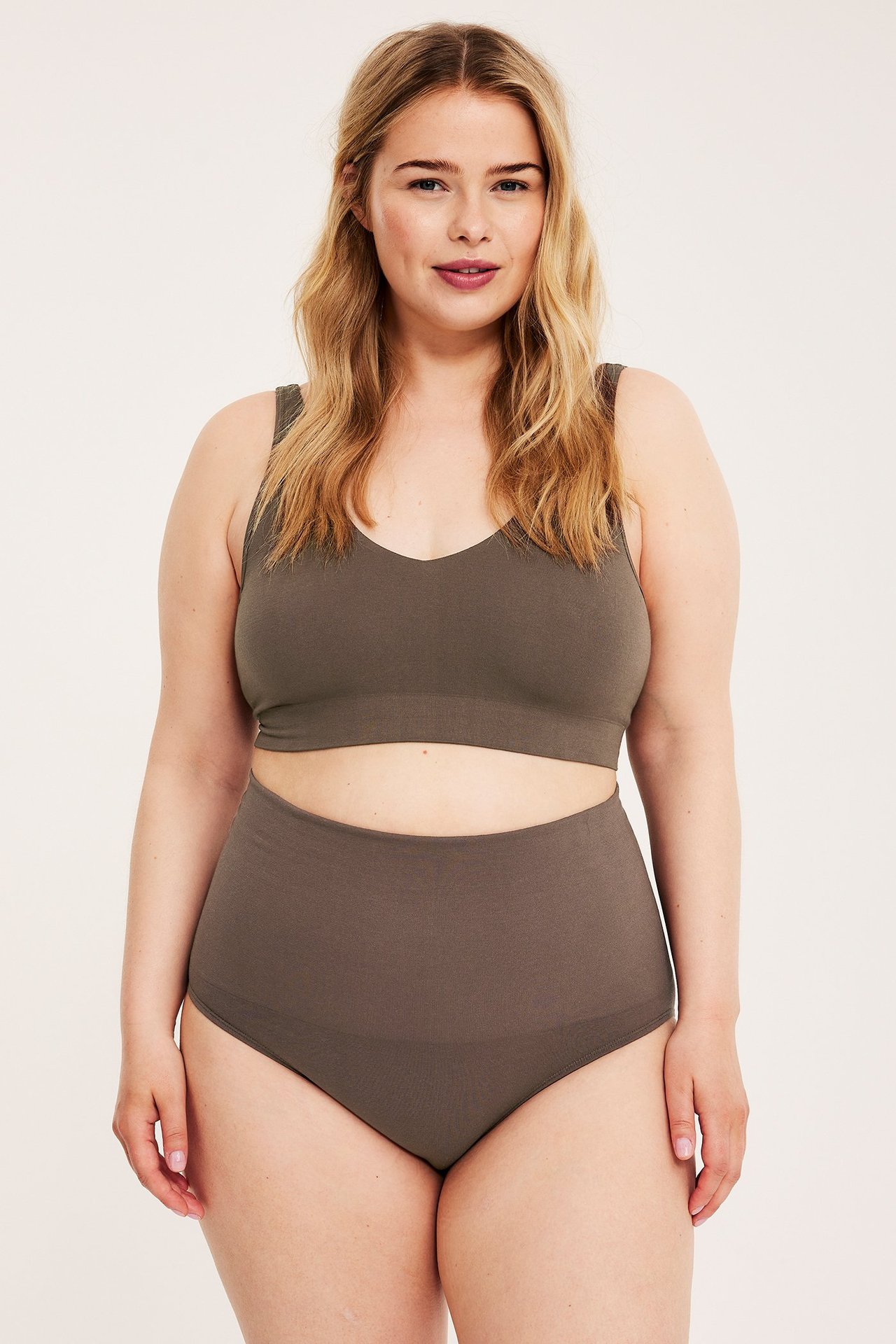 Widok z przodu: kobieta w ciemnobrązowych bezszwowych majtkach z wysokim stanem i pasującym biustonoszu.