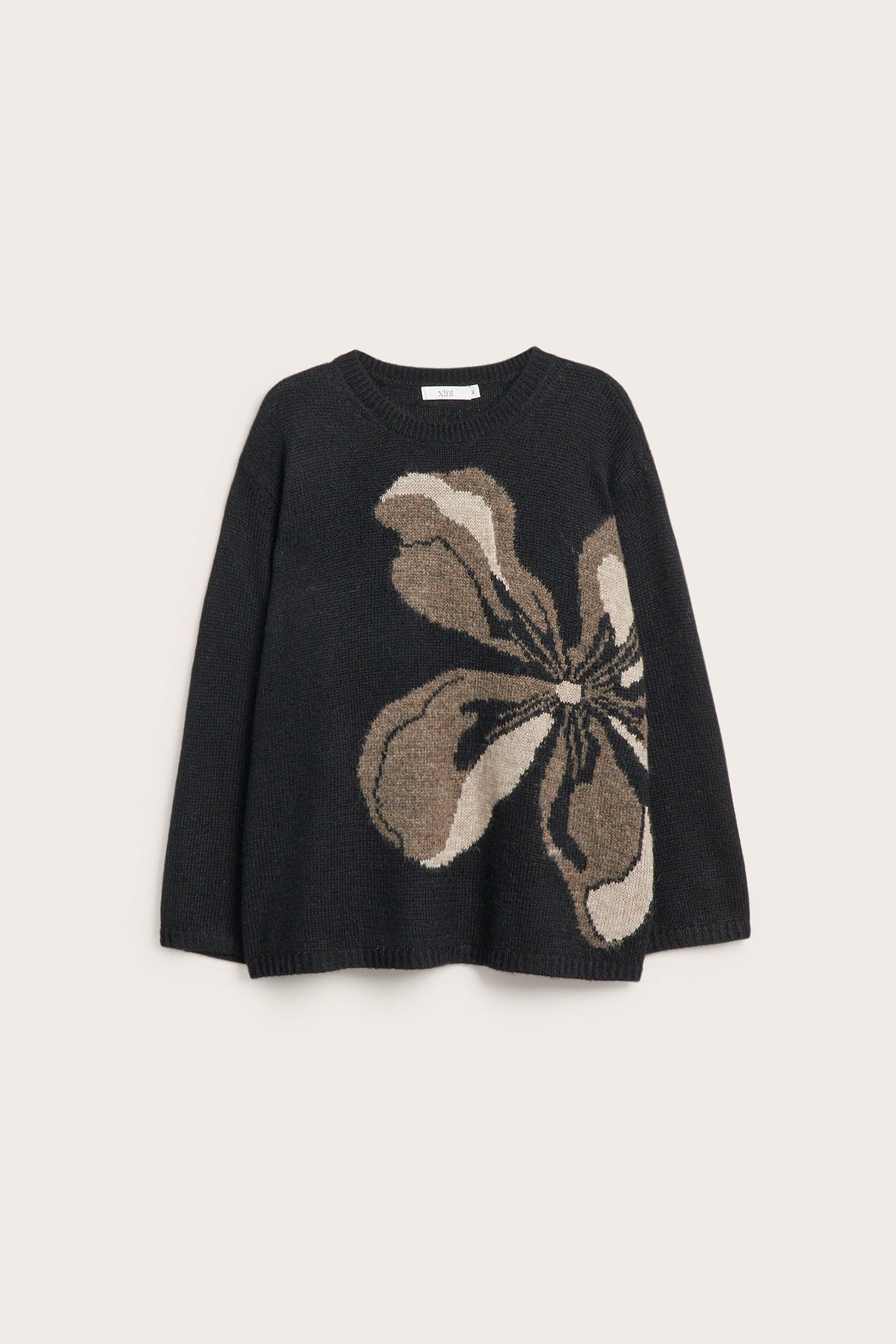 Edestä: musta neulepusero, jossa suuri ruskea ja beige kukkakuvio.