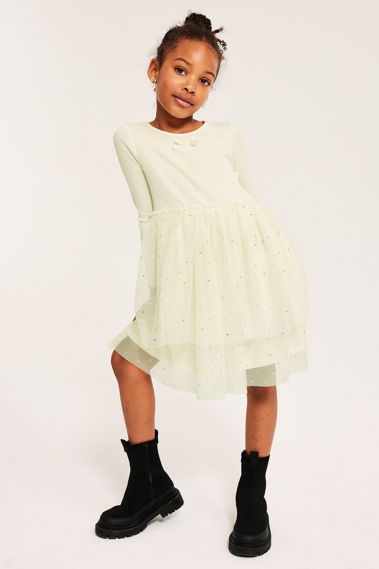 Flicka i ljusgul klänning med trikå, silverströmmad tyllkjol, mönstrad.