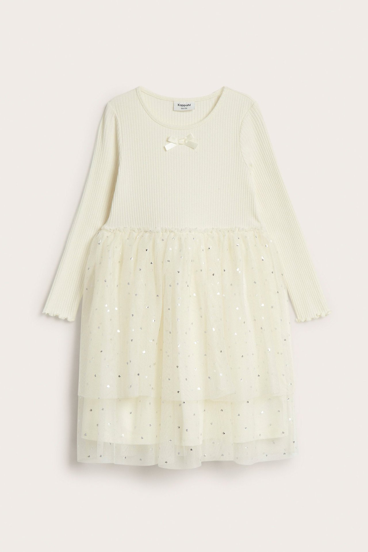 Framsida: Vit barnklänning i ribbad trikå med silverprickig tyllkjol i lager och liten rosett.