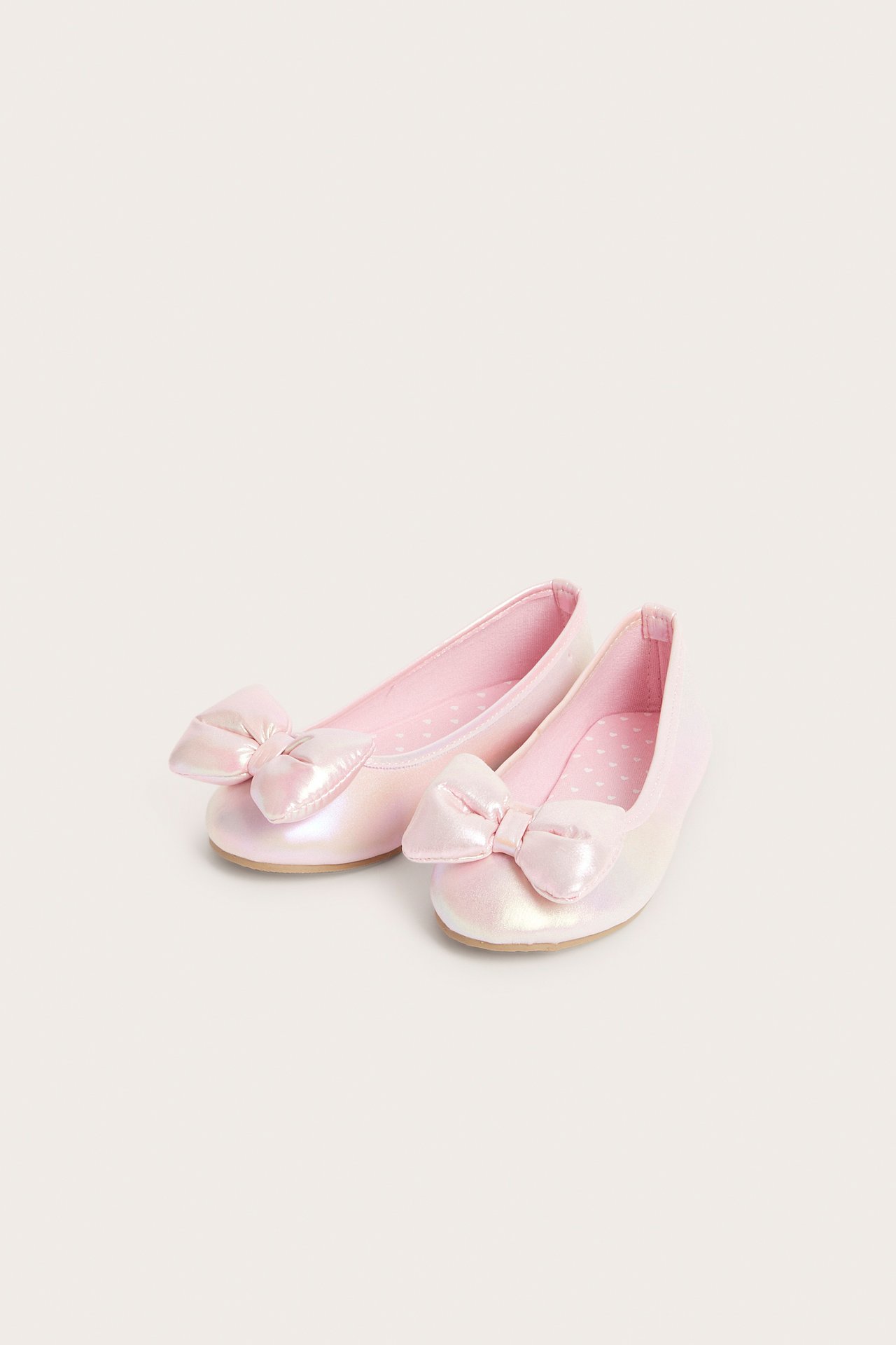 Ovenfra-visning av to lysrosa, iriserende ballerinasko med stor puffsløyfe og prikkete fôr.