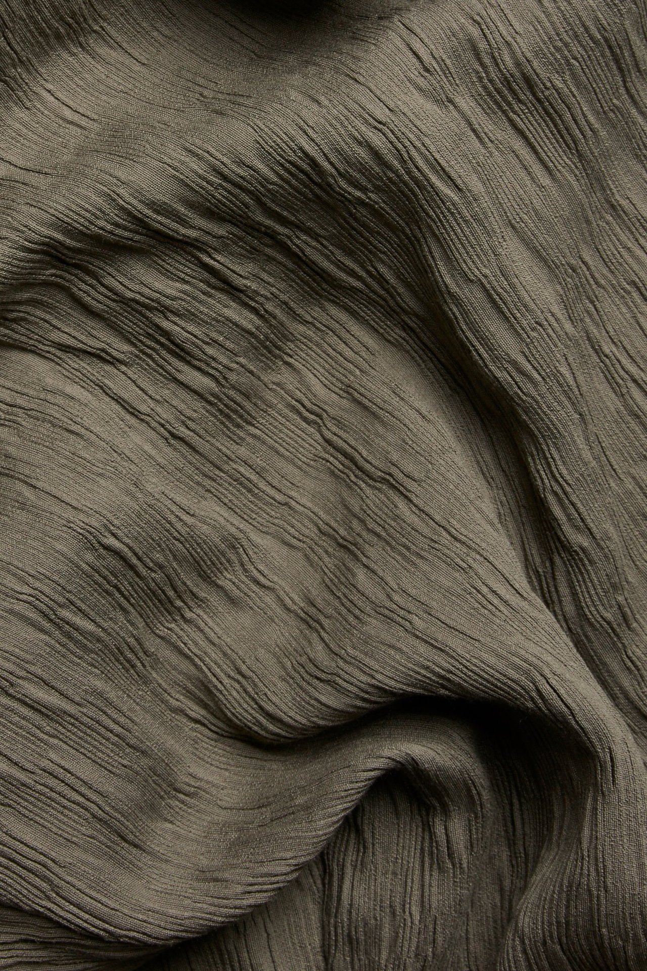 Zbliżenie na brązowy, jednolity materiał spodni pull-on z marszczoną fakturą.