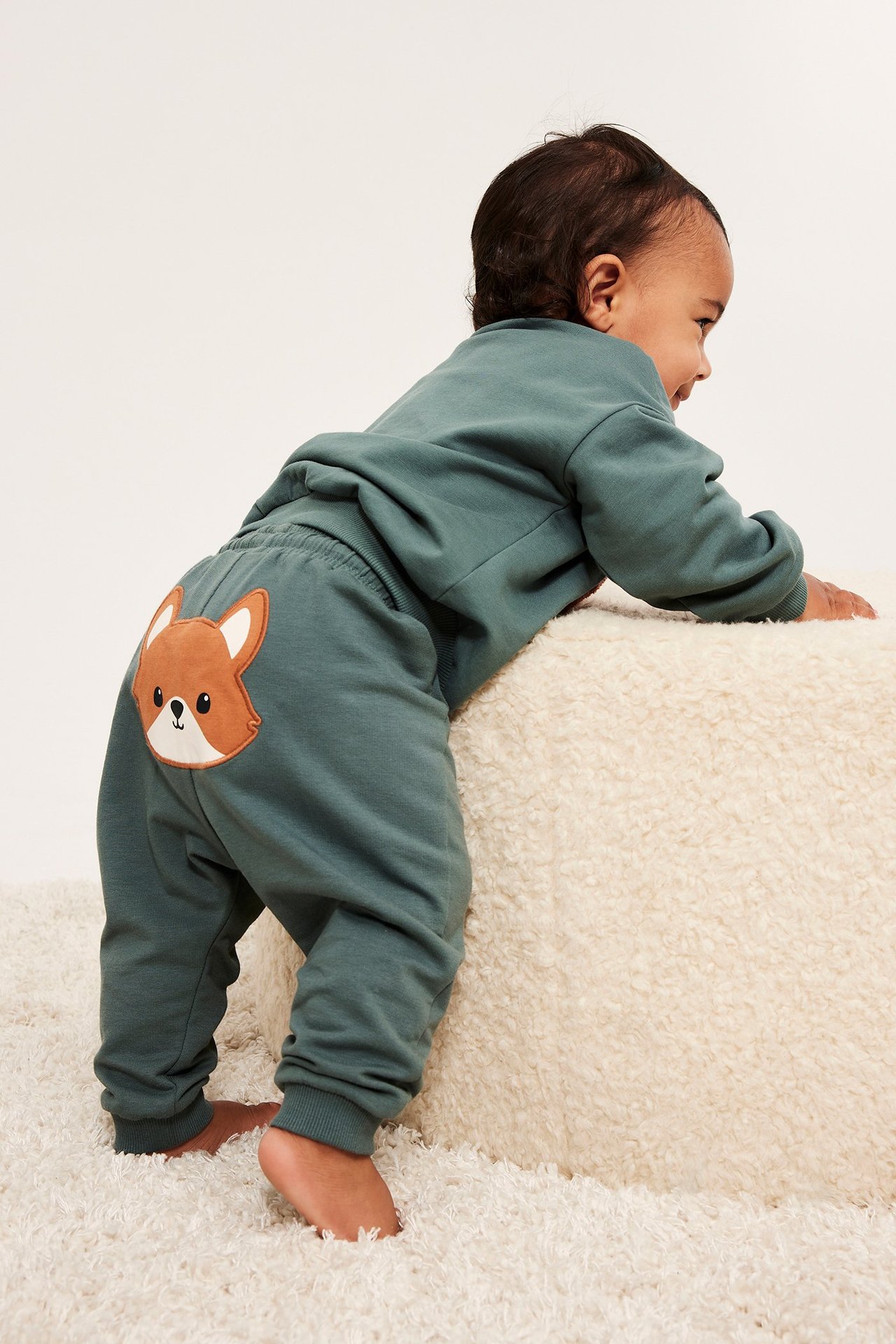 Takaa: Vauva khakinvihreissä collegehousuissa, joissa kettusovellus takana, ja yhteensopivassa paidassa.