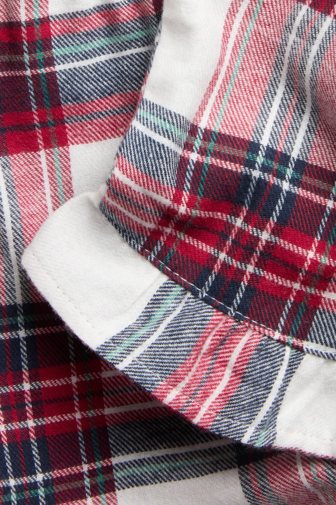 Zbliżenie czerwonych, białych, granatowych i zielonych flanelowych szortów w kratę z małą falbanką.