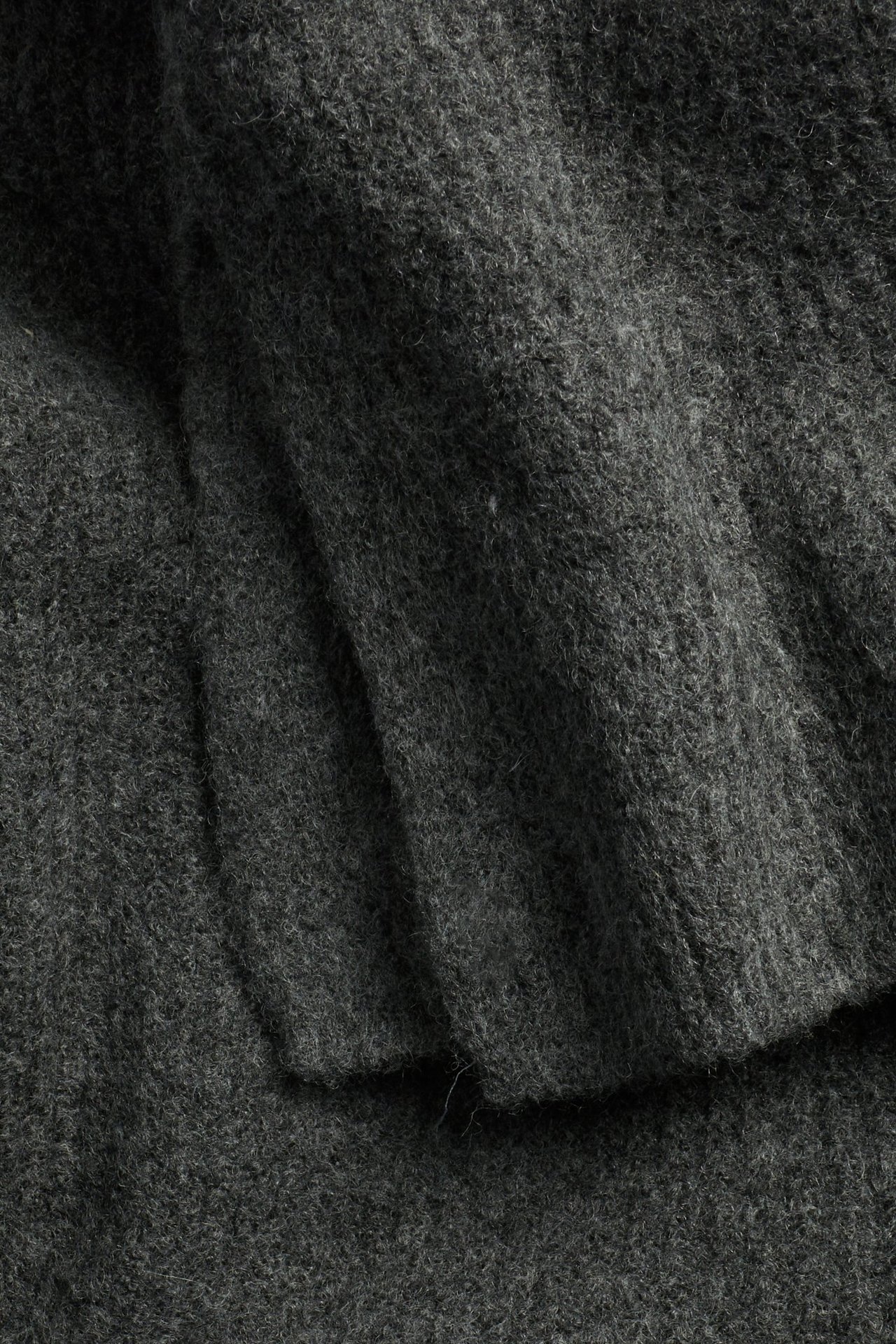 Zbliżenie ciemnoszarego swetra z dzianiny prążkowanej o strukturalnym wzorze.