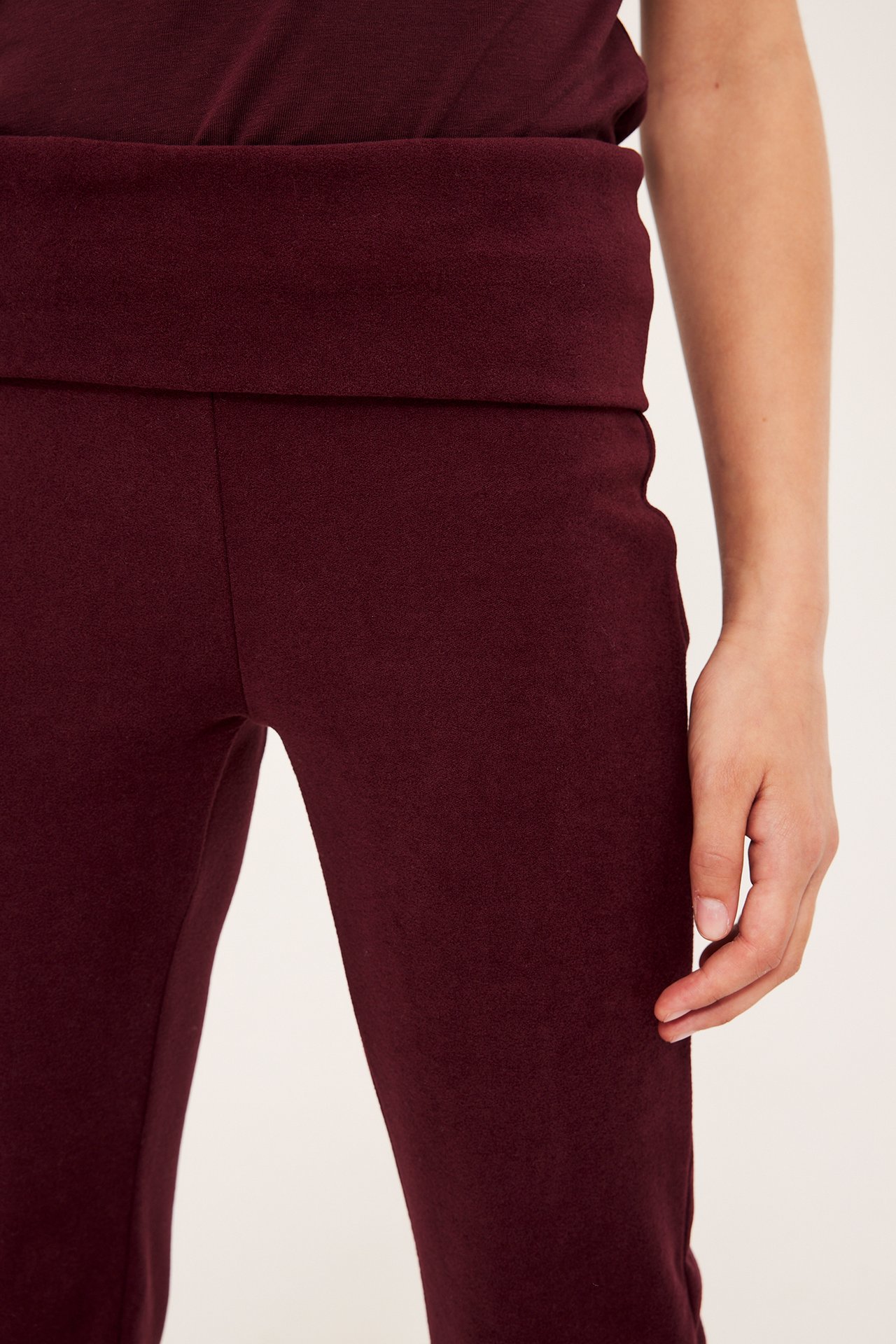 Närbild på ett barn i mörkröda utsvängda leggings med nedvikbar midja och matchande topp.