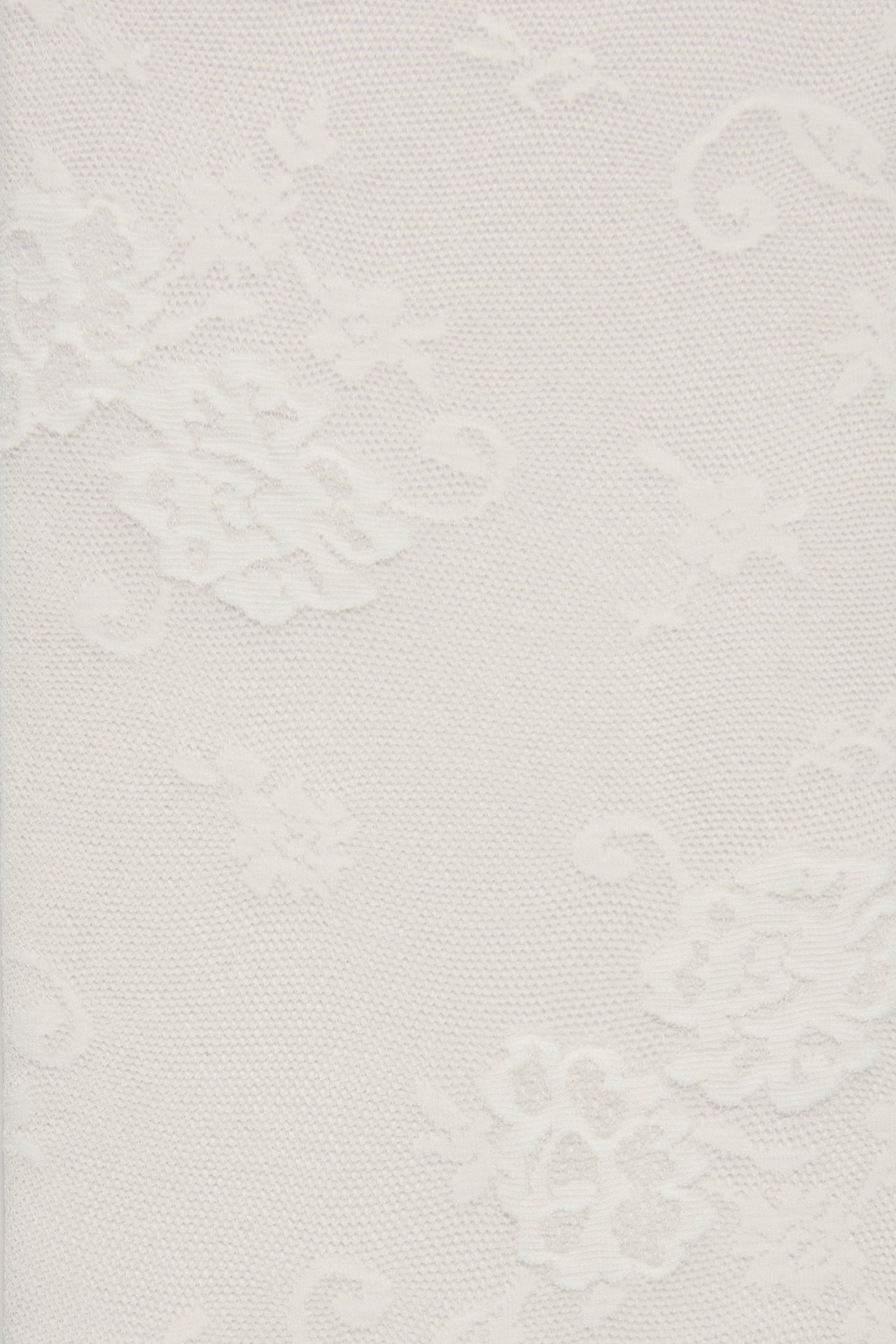 Närbild av offwhite tunna strumpor med ett delikat blommigt spetsmönster.