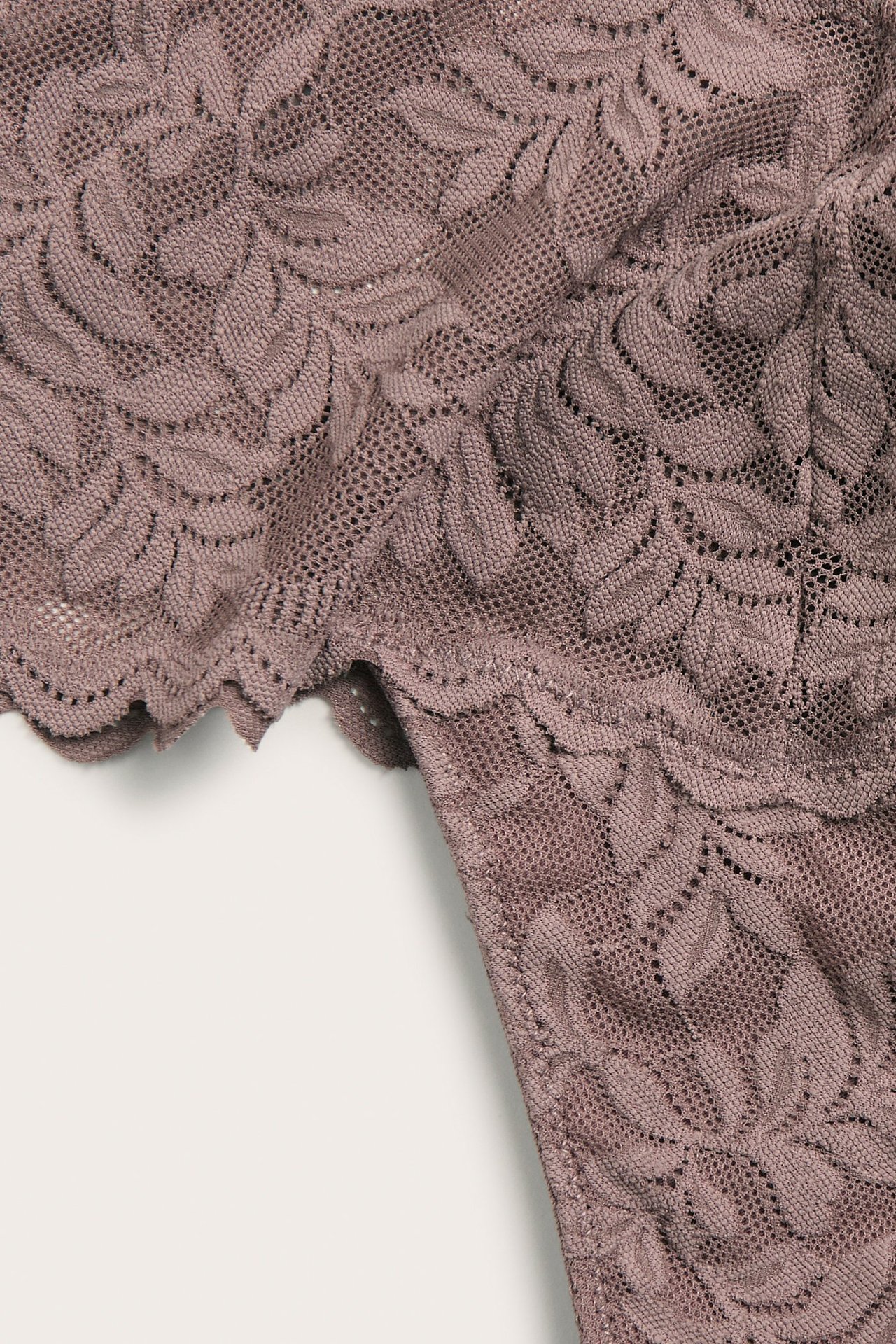 Zbliżenie na ciemnoróżowe koronkowe stringi z kwiatowym wzorem.