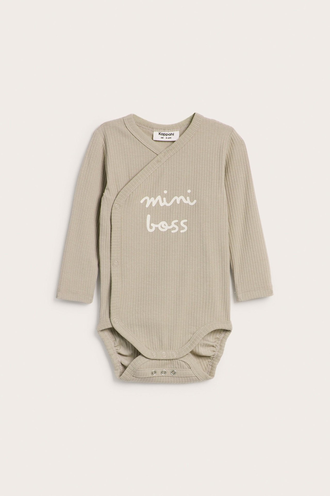 Edestä: Hiekanvärinen ribbineuleinen vauvan body pitkillä hihoilla, kietaisumallilla, neppareilla ja "mini boss" -painatuksella.
