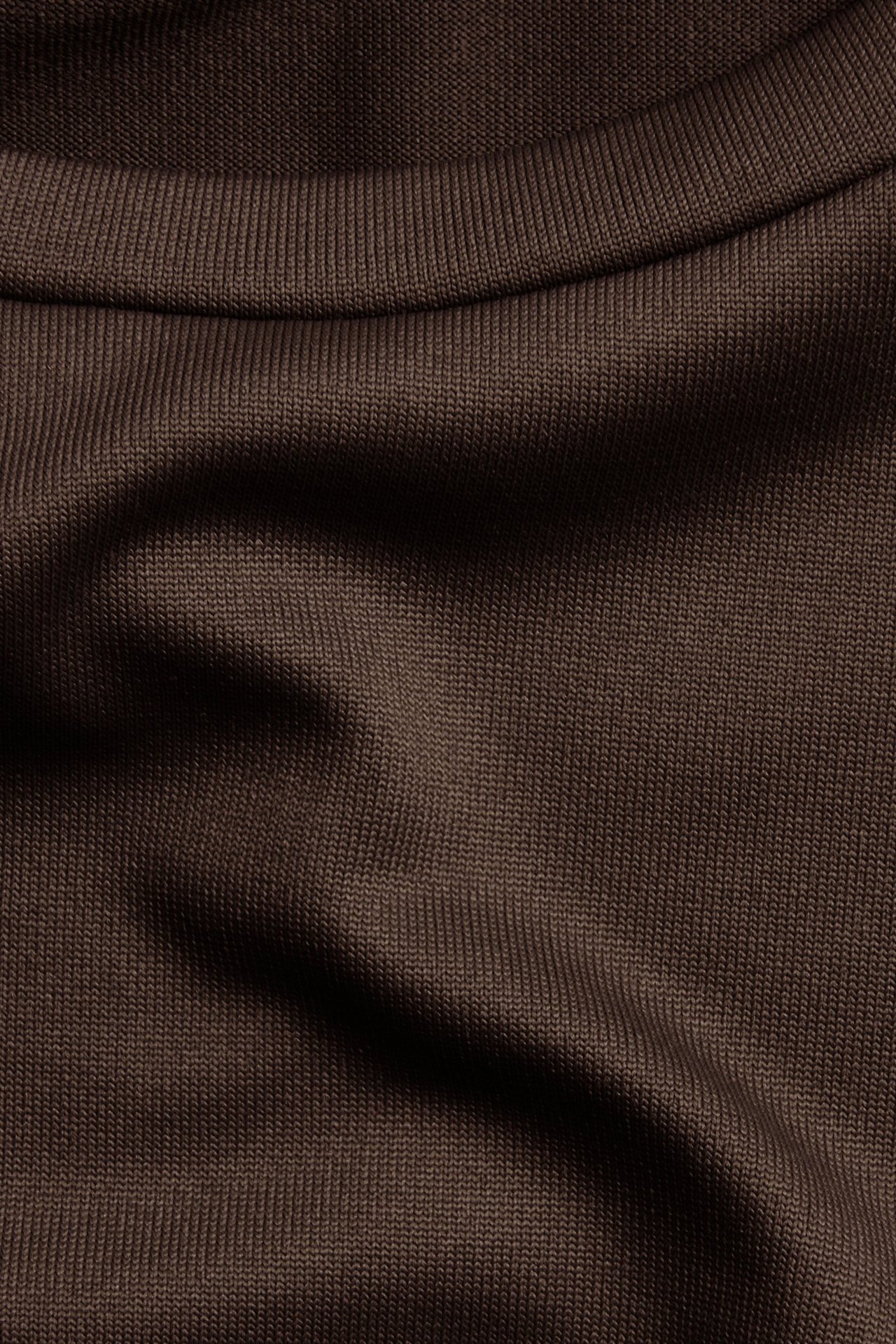 Zbliżenie na ciemnobrązowy, prążkowany top z długim rękawem i okrągłym dekoltem.