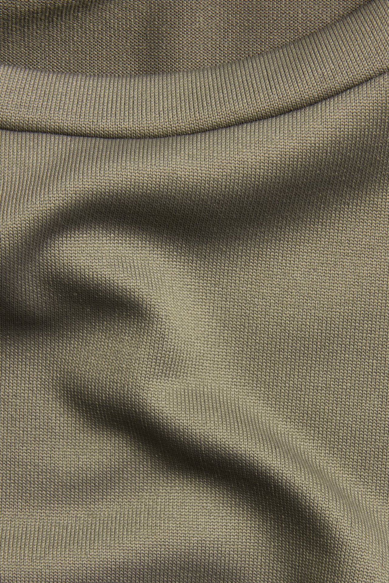 Zbliżenie brązowego, prążkowanego topu z długim rękawem i okrągłym dekoltem.