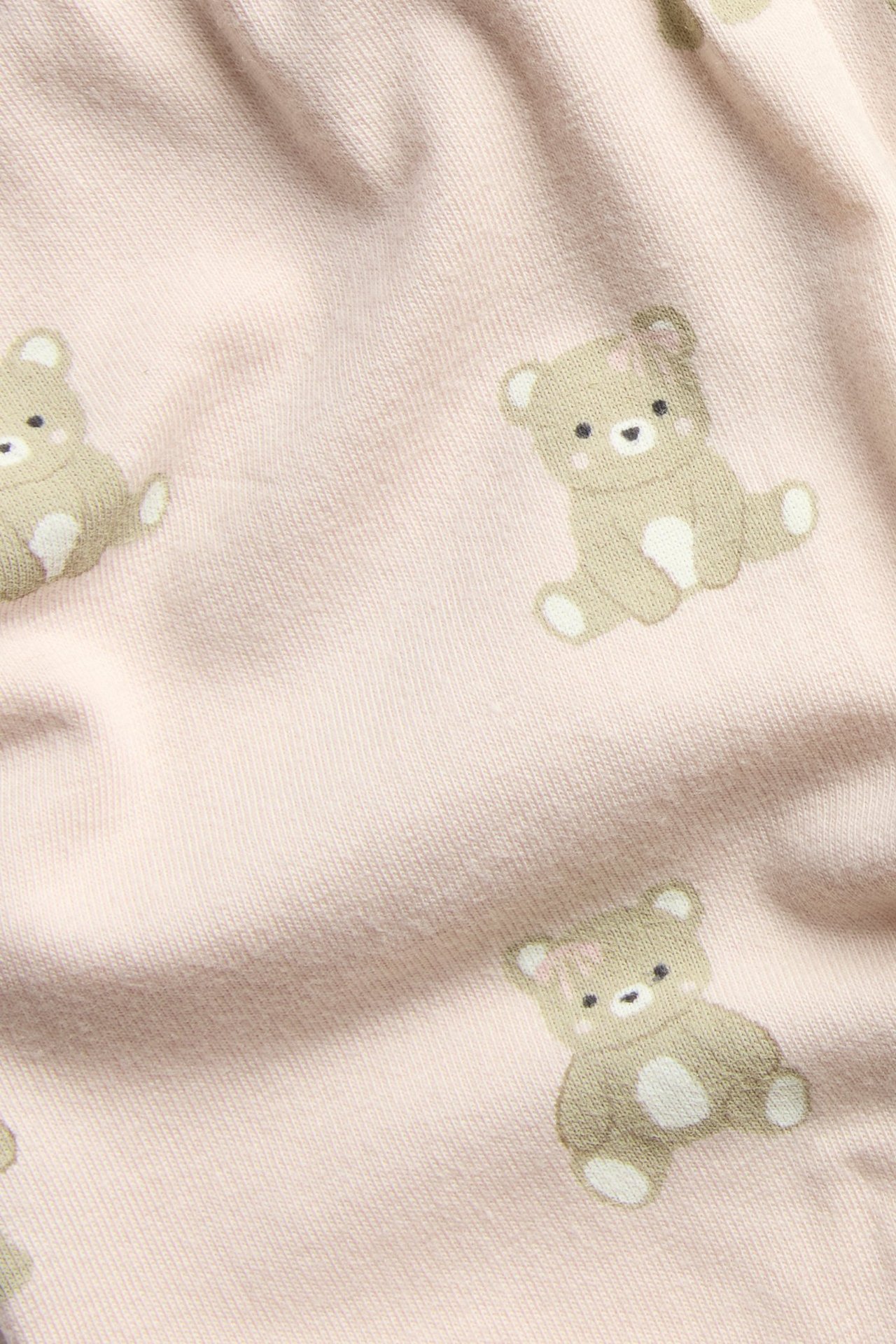 Nærbilde av rosa baby leggings stoff med et søtt bamsemønster.