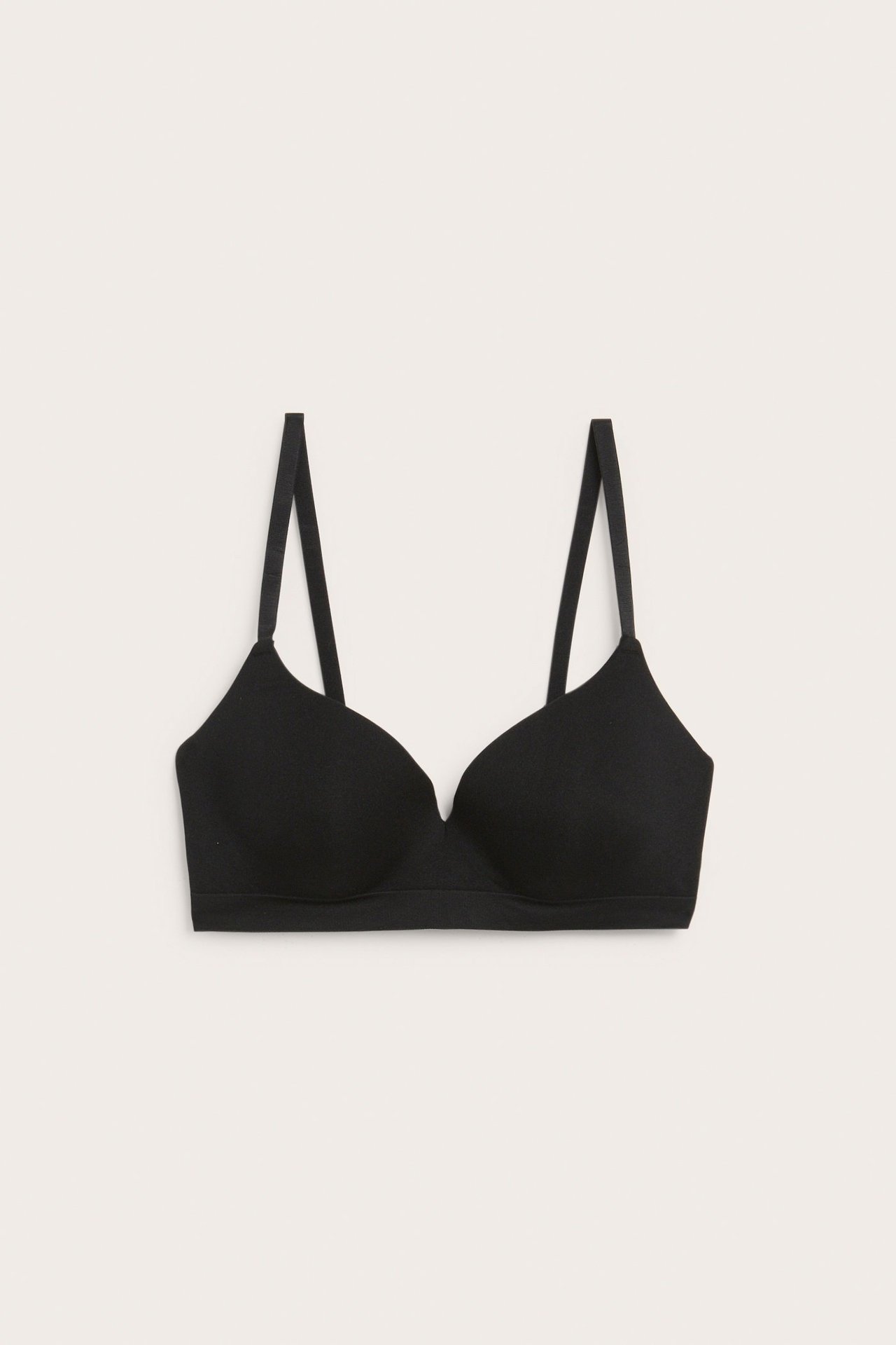 Frontbilde av en svart sømløs push-up-BH med justerbare stropper, flatlagt.