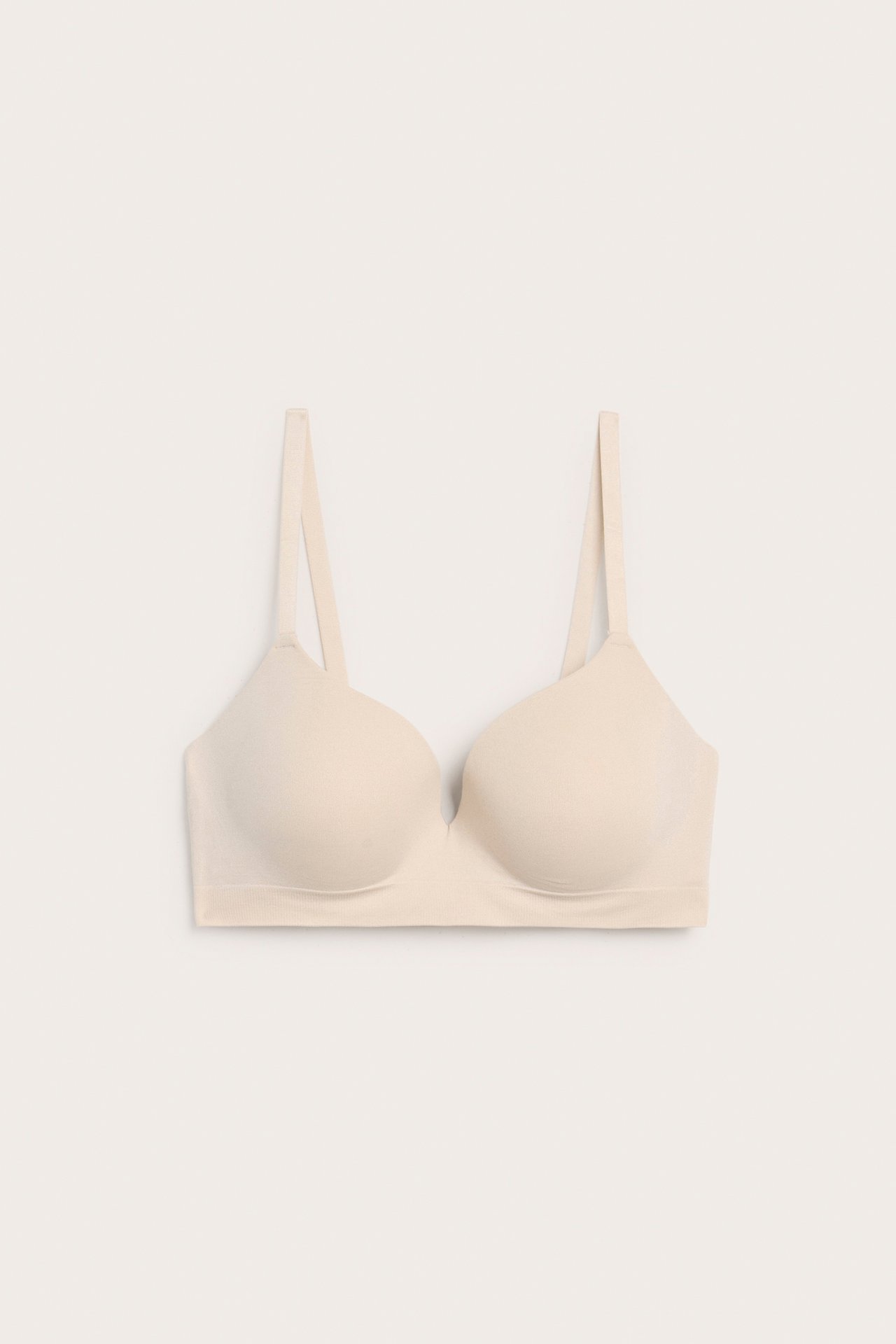 Forfra av en lys rosa sømløs push-up BH med justerbare stropper.