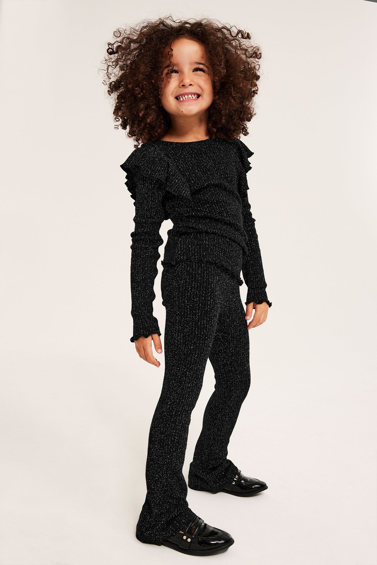 Lapsi mustissa kimaltelevissa ribatuissa levenevissä leggingseissä, yhteensopivassa topissa ja mustissa loaferit.
