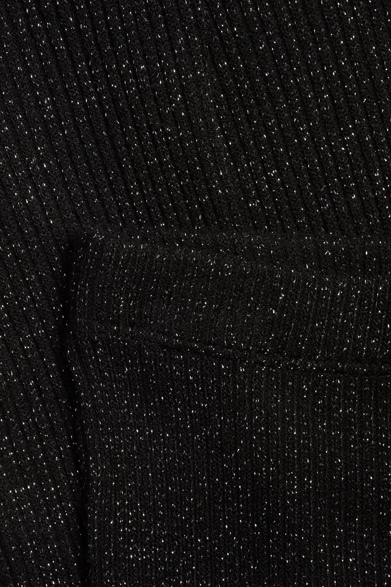 Zbliżenie czarnego prążkowanego materiału legginsów ze srebrnym brokatem.