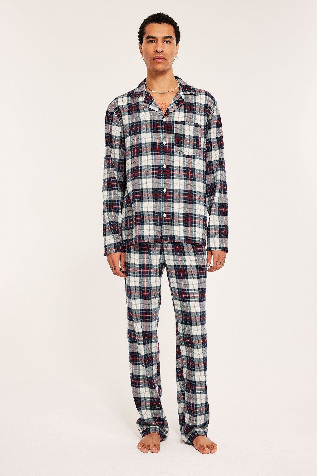 Mies tummansinisessä ruudullisessa flanelliyhdistetyissä pyjamissa, etunäkymä.