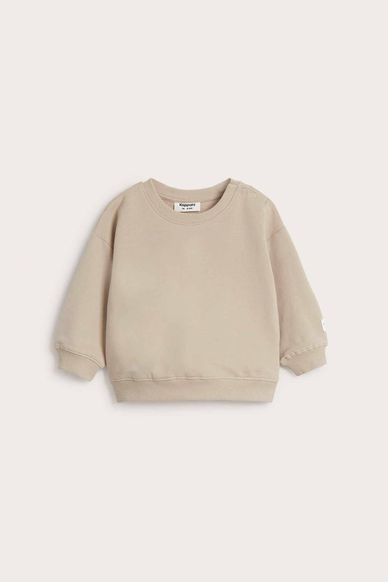 Edestäpäin, beige vauvan collegepaita harjatulla sisäpinnalla ja painonapeilla olalla.