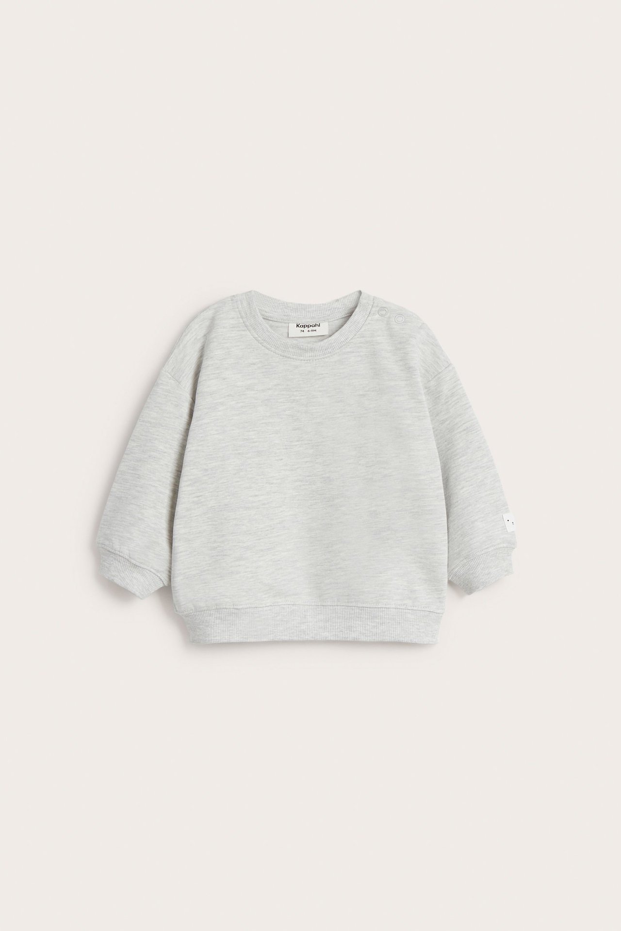 Frontvy av en babytröja i ljusgråmelerad sweatshirt med tryckknappar på axeln och ribbade muddar.