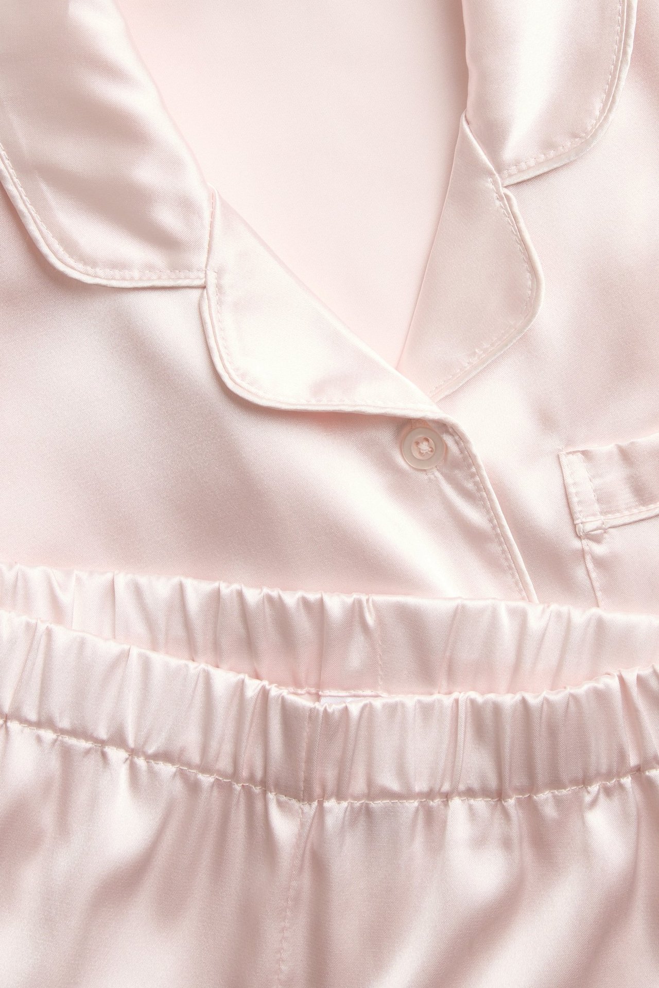 Zbliżenie jasnoróżowej piżamy satynowej z kołnierzykiem i spodniami z elastycznym pasem.
