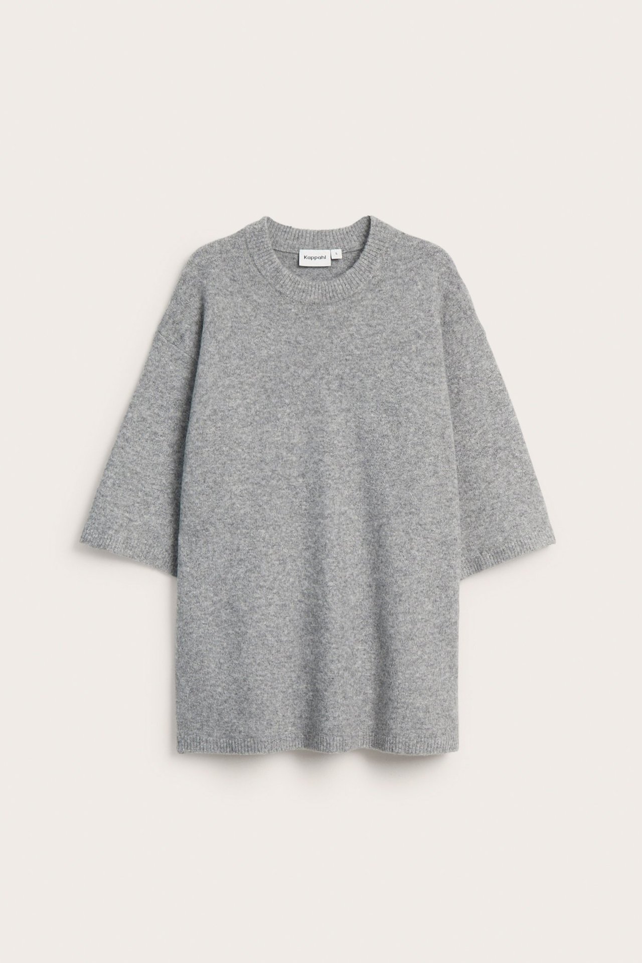 Edestä kuvattu vaaleanharmaa oversized neulepusero lyhyillä hihoilla ja pyöreällä pääntiellä.
