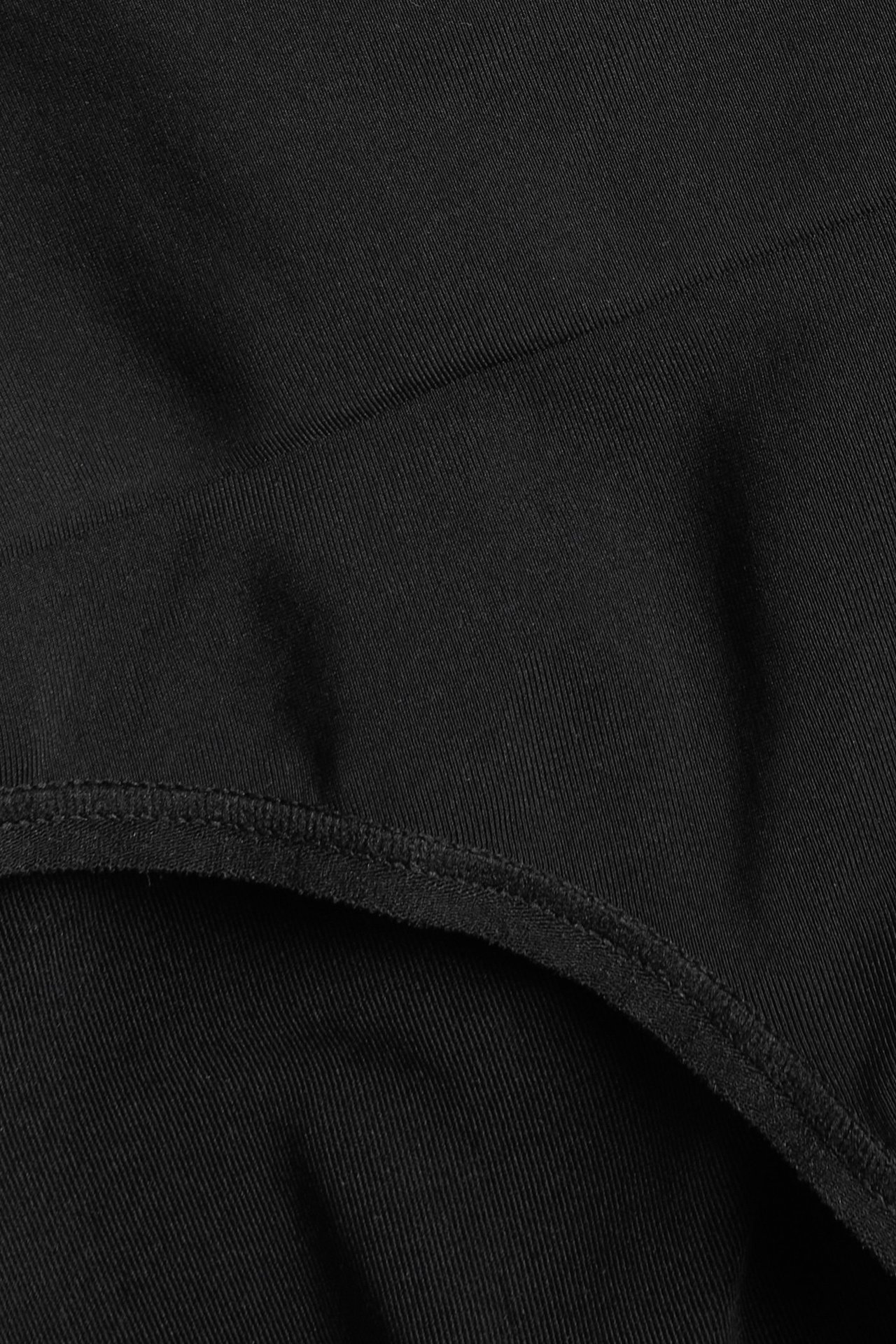 Zbliżenie na czarne, gładkie, jednolite figi modelujące z tkaniny poliamidowo-elastanowej.