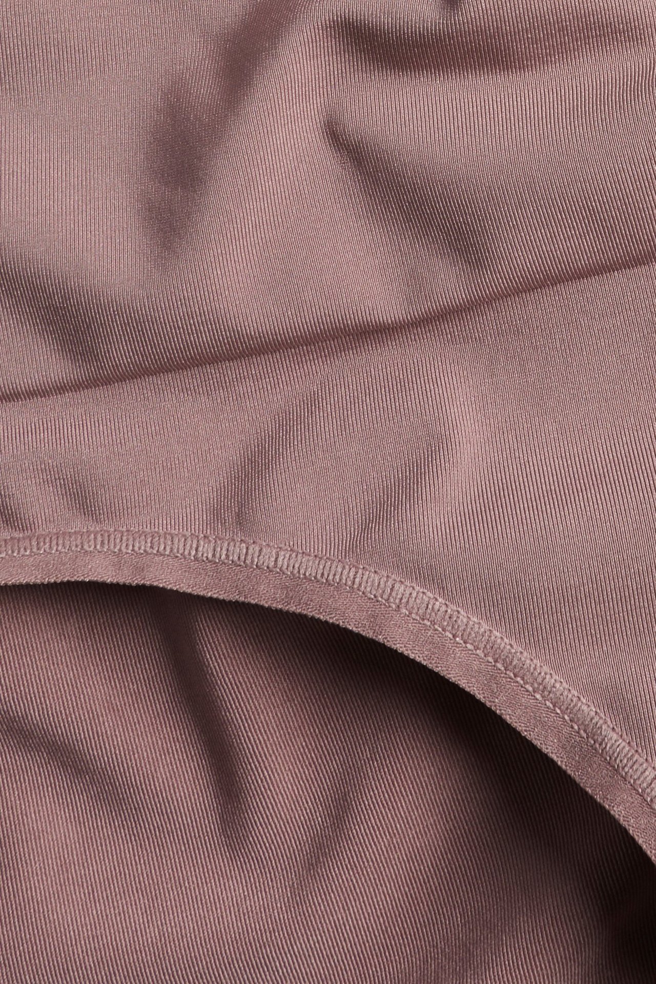 Zbliżenie na ciemnoróżowe, gładkie, prążkowane figi modelujące z poliamidu i elastanu.