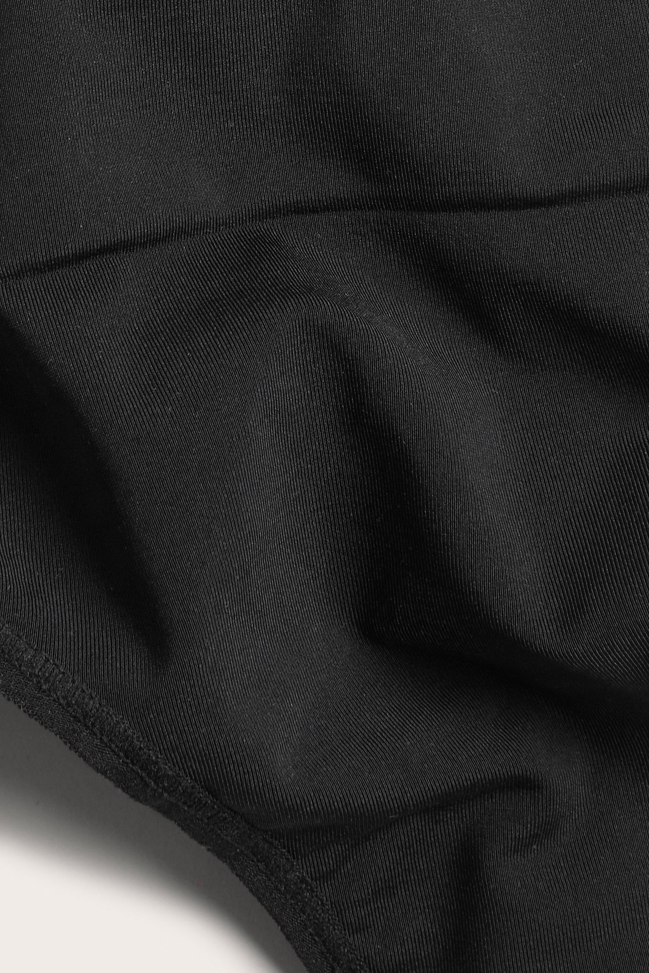 Zbliżenie na czarne, jednolite stringi modelujące z prążkowaną fakturą.