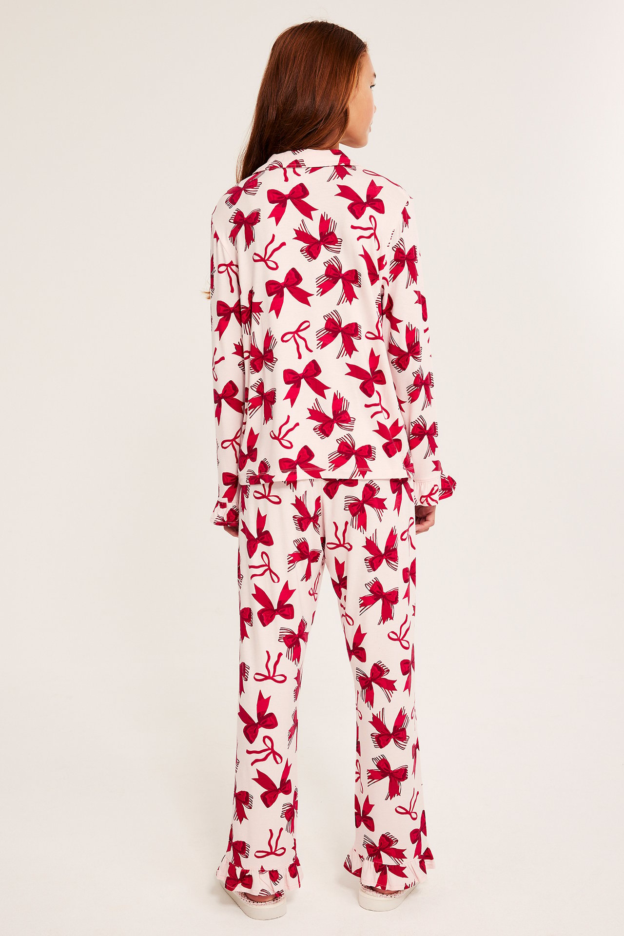 Långärmad mönstrad pyjamas i trikå, ljusrosa färg med röda rosetter och strumpor.