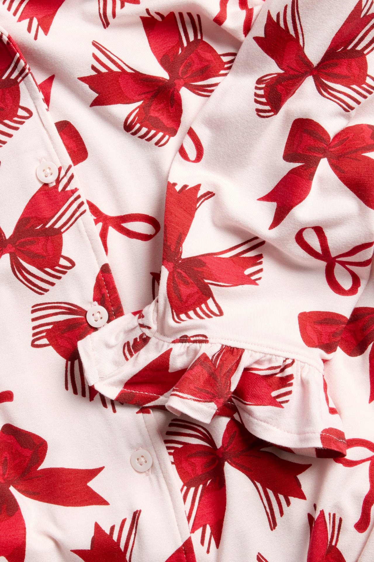 Różowa piżama z długim rękawem, wzór w kokardki, falbanki na końcu rękawów.