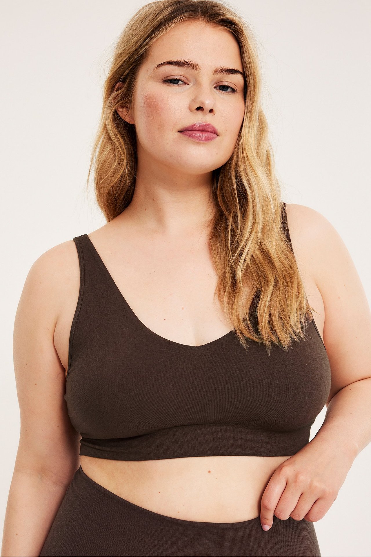 Frontvy av en kvinna i en mörkbrun sömlös bh med V-ringning i bomullsmix och matchande trosa.