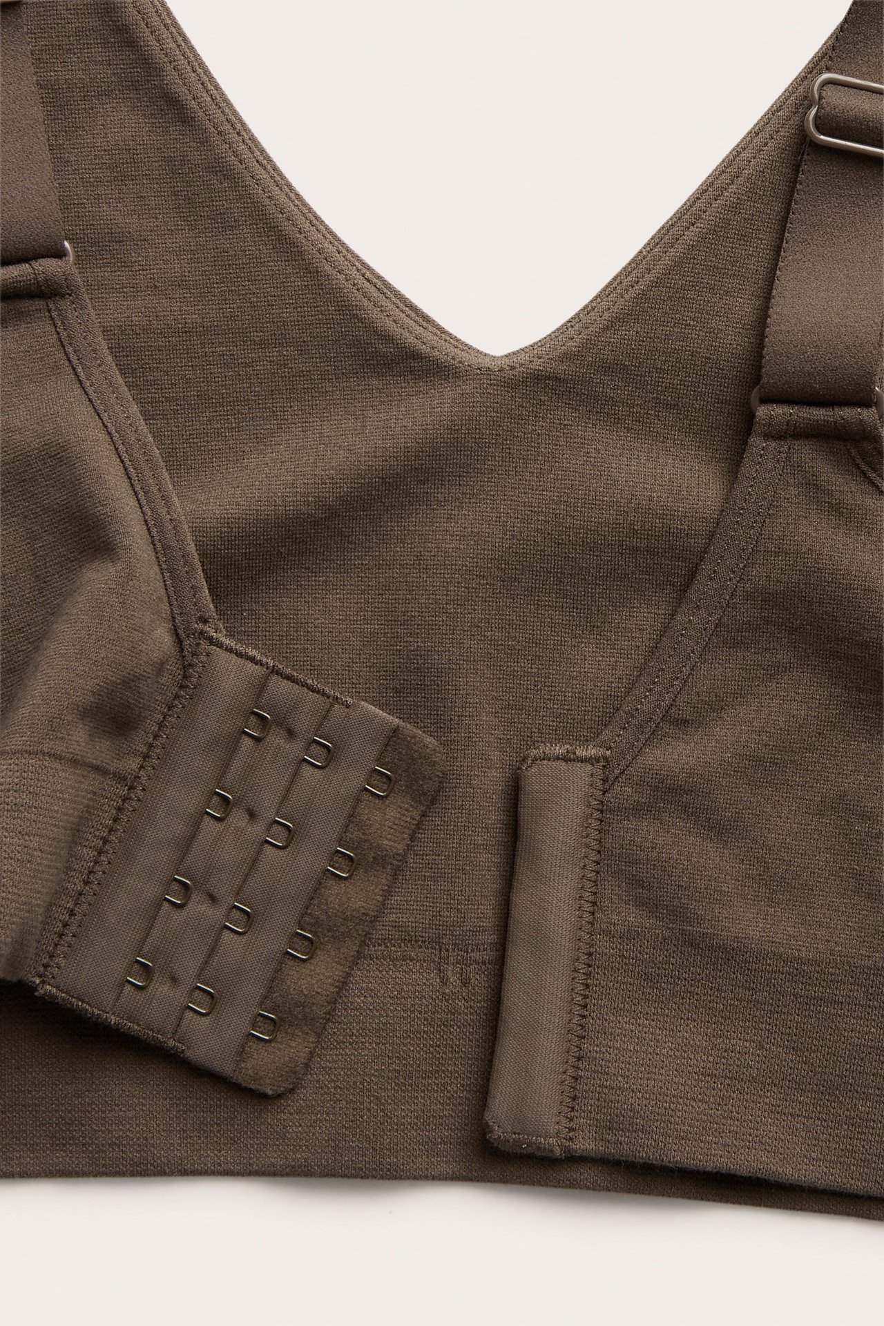 Zbliżenie na ciemnobrązowy, bezszwowy biustonosz z mieszanki bawełny z zapięciem na haftki i regulowanymi ramiączkami.