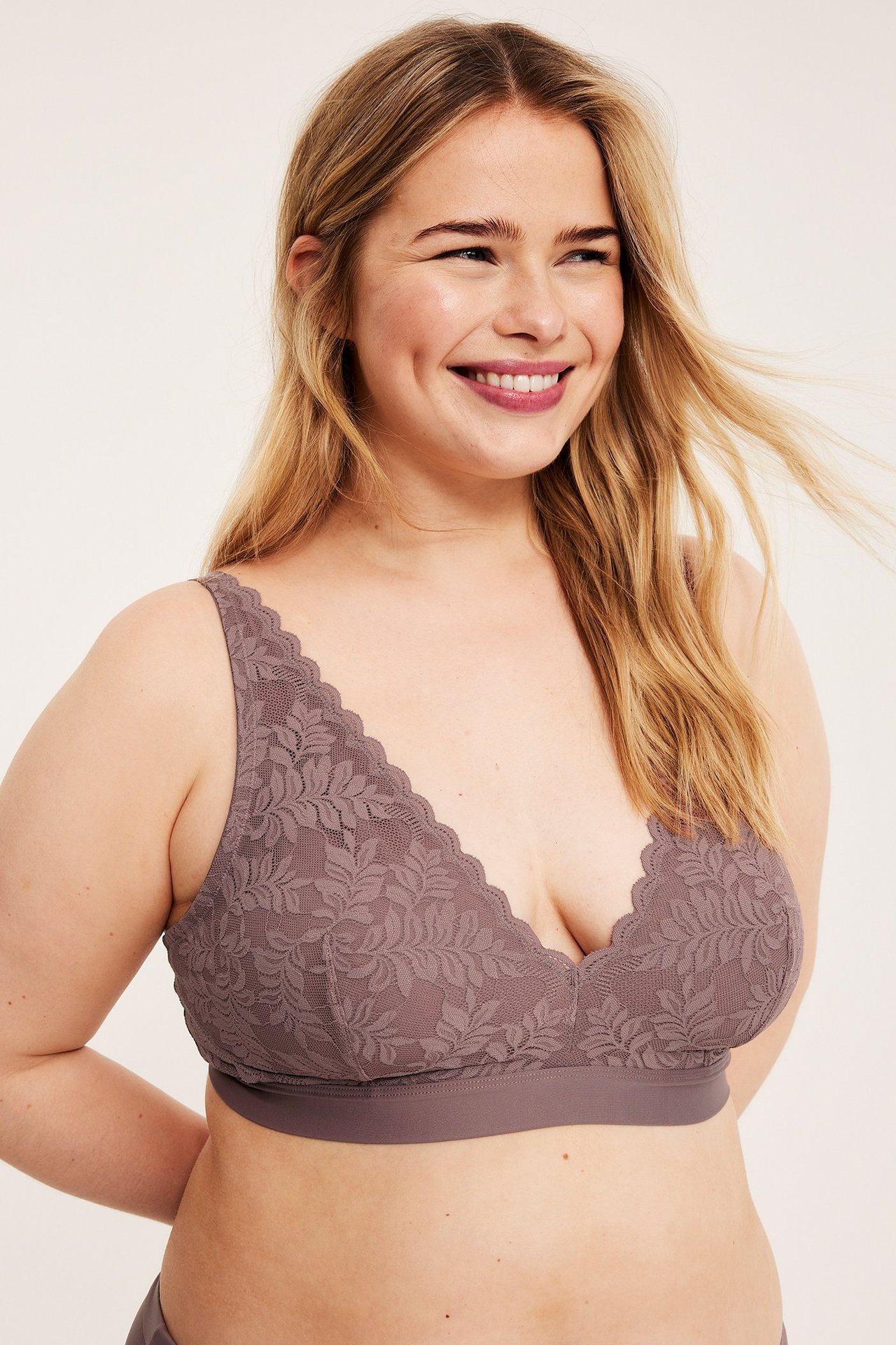 Framifrån, kvinna i en mauvefärgad spets-bralette med elastiskt band.