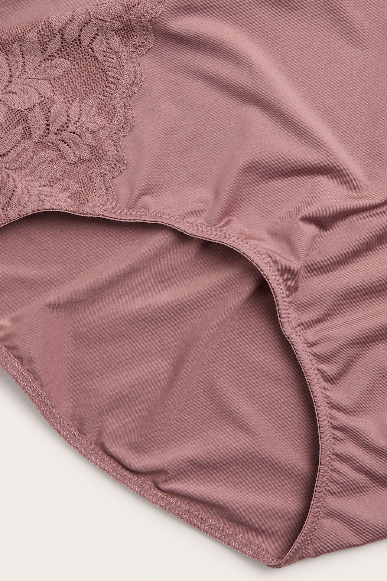 Zbliżenie na ciemnoróżowe majtki z mikrofibry z koronkowymi aplikacjami i elastycznym pasem.
