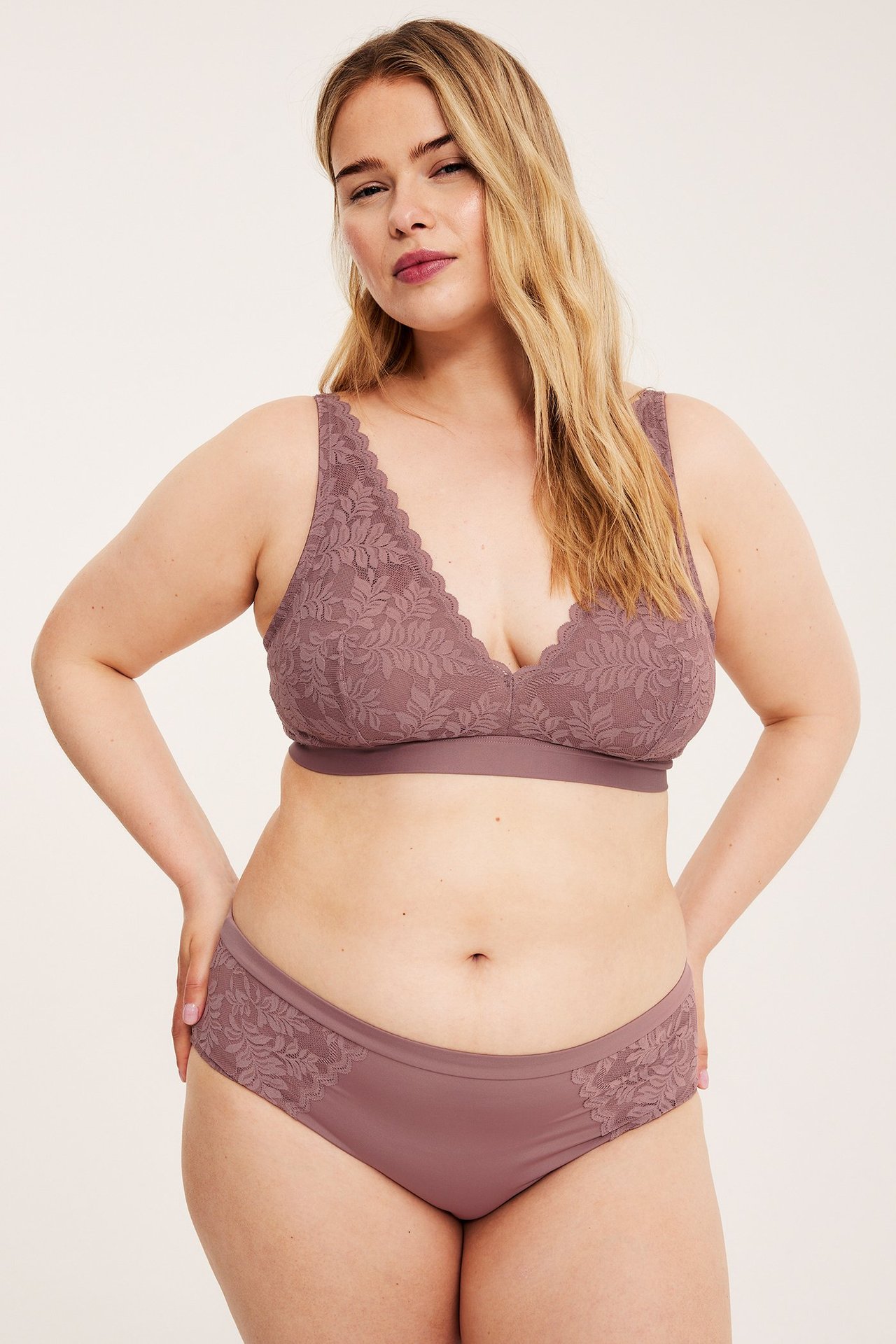 Forfra, kvinne i mørk rosa blondetruse med matchende bralette.