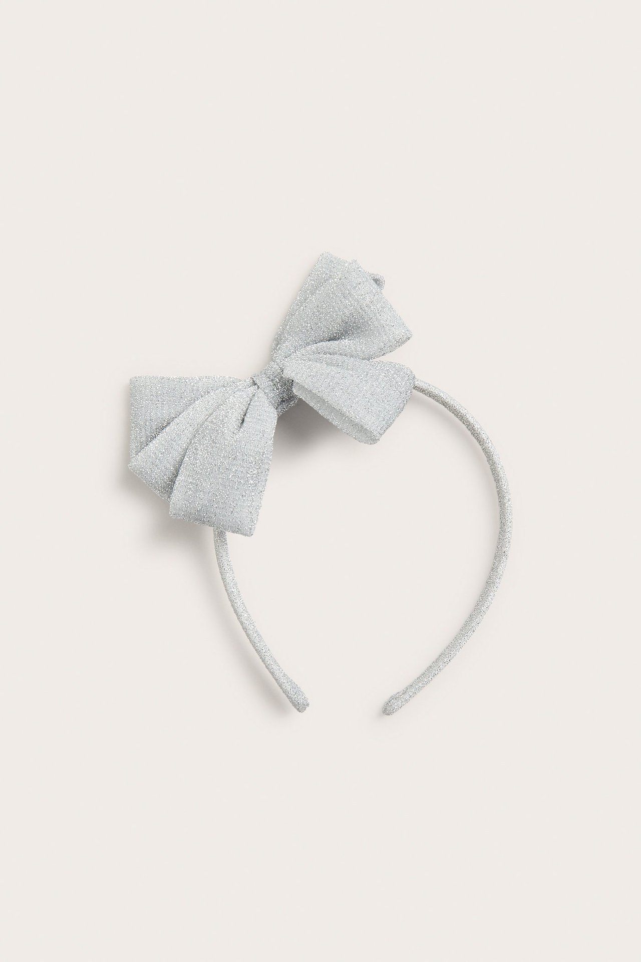 Widok z góry na srebrną opaskę z lureksu z dużą kokardą.