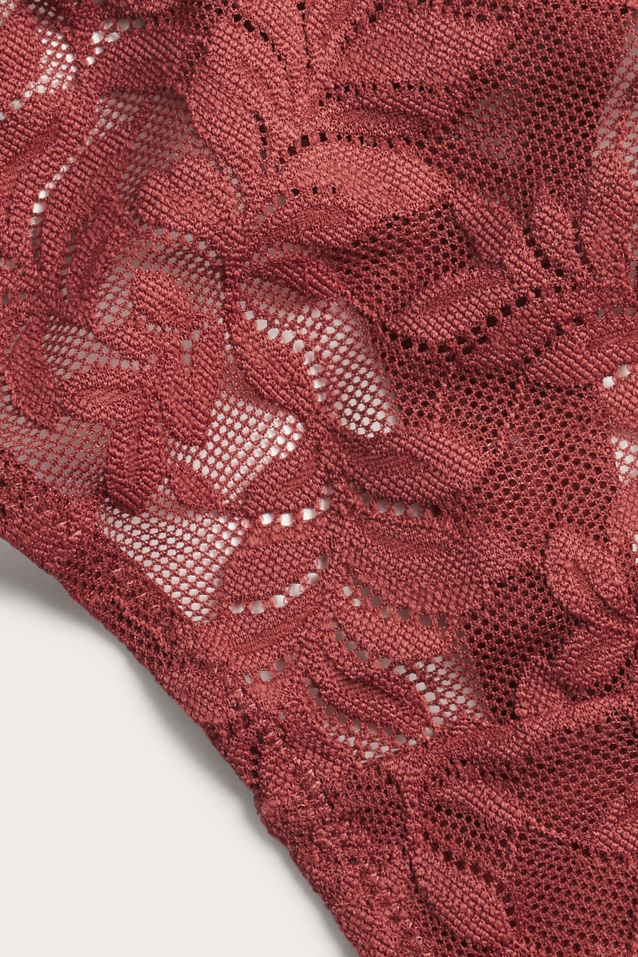 Zbliżenie na czerwone koronkowe stringi z kwiatowym wzorem.