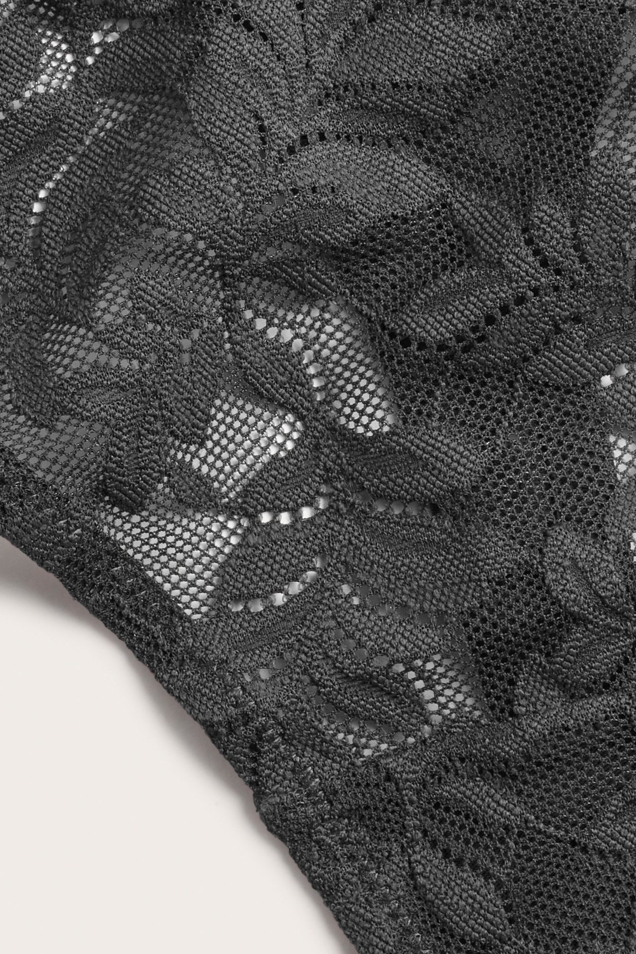 Zbliżenie czarnych koronkowych stringów damskich z kwiatowym wzorem.