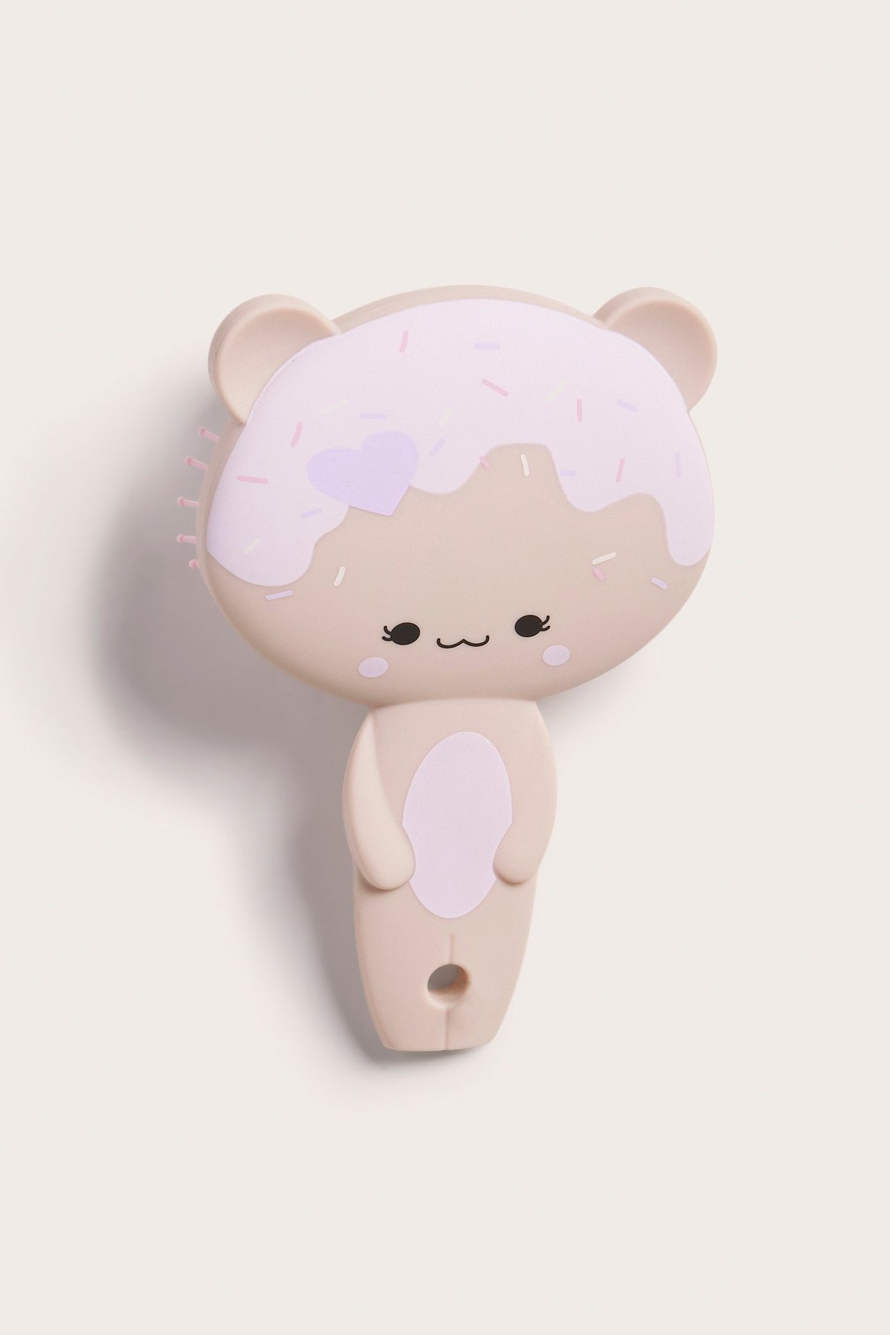 Widok z przodu jasnobeżowej plastikowej szczotki dla dzieci, w kształcie misia z nadrukiem pączka.